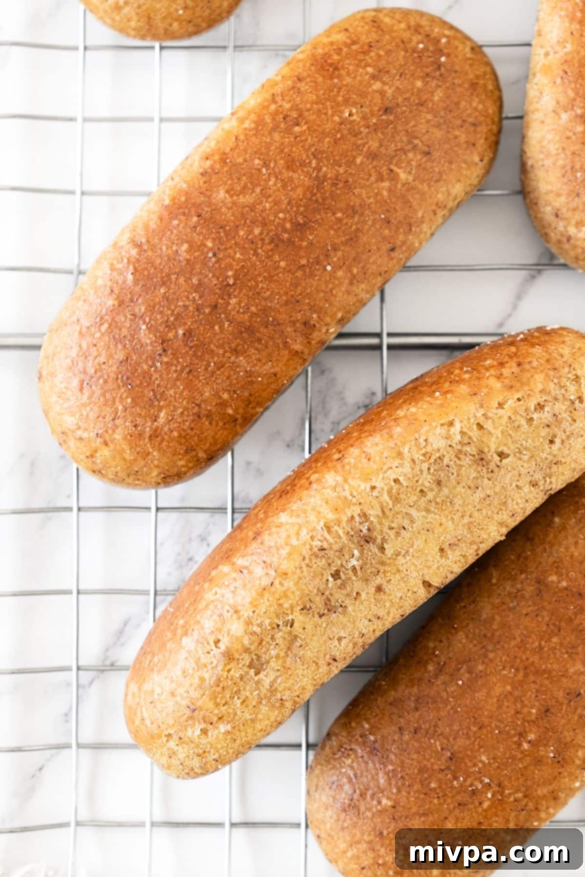 Homemade Gluten-Free Hot Dog Buns (Dairy-Free) Top down view of hot dog buns on wire rack.