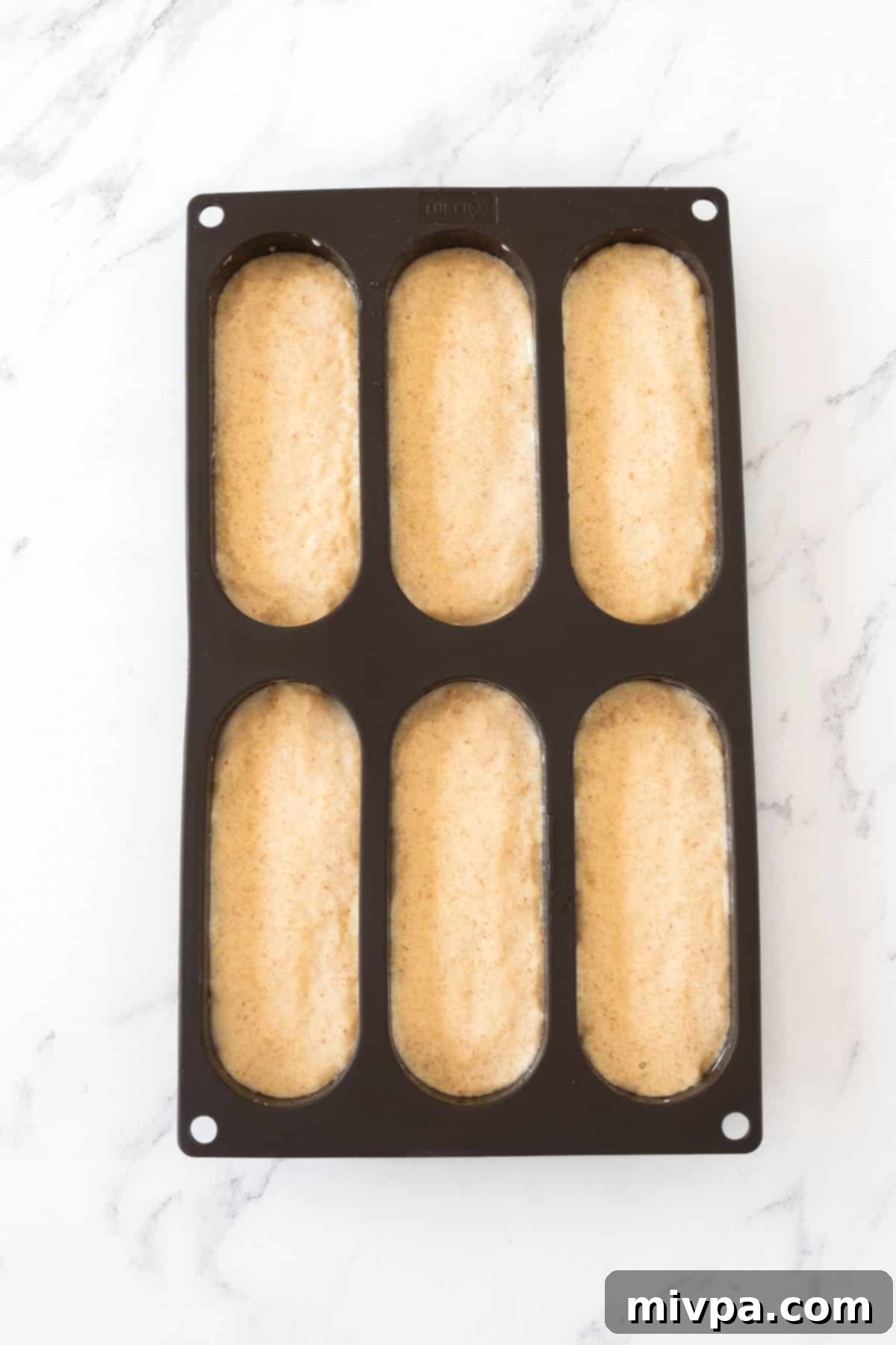 How to Make Hot Dog Buns Top down view of gluten-free dough in hot dog mold.