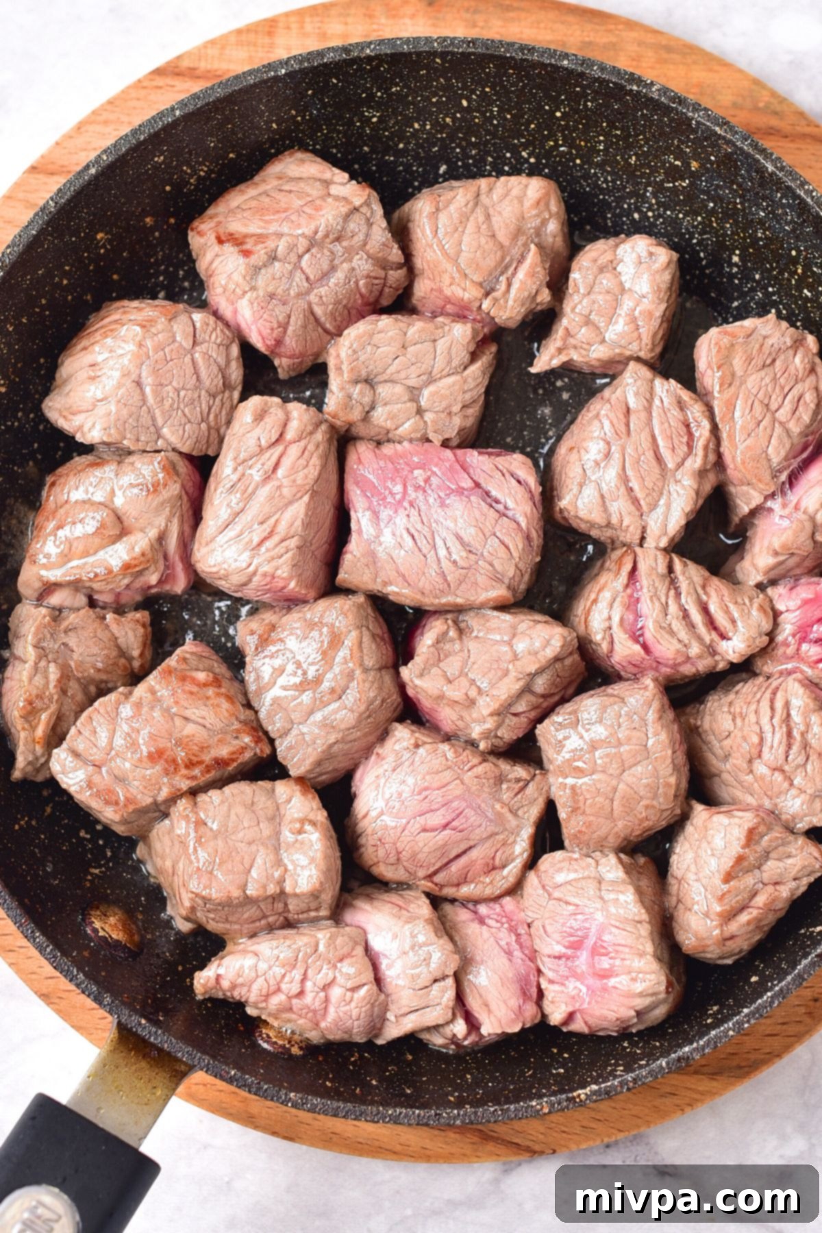 Searing cubed beef pieces in a hot skillet until golden brown.