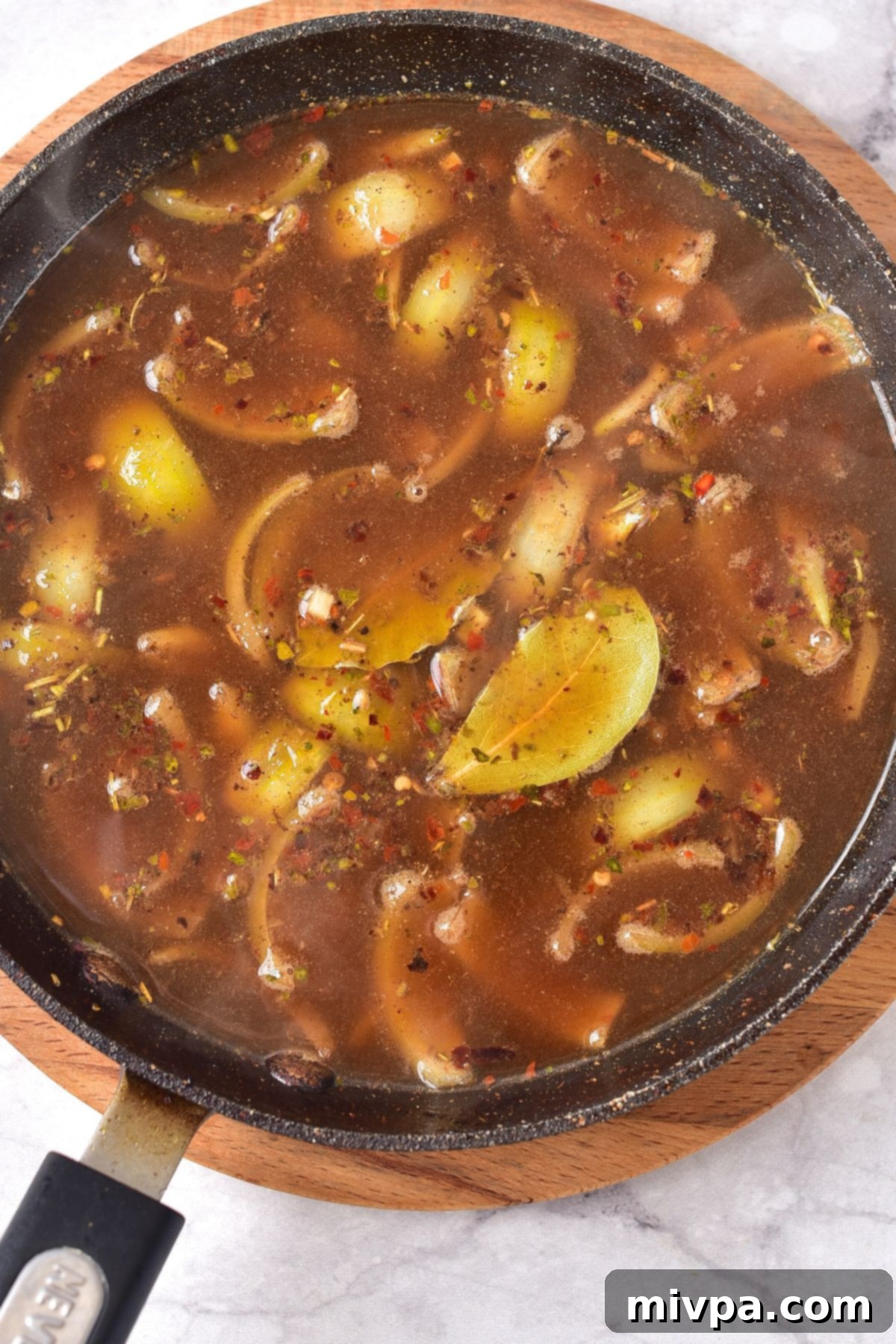 Cooking vegetables in beef broth and apple cider vinegar, simmering to combine flavors.