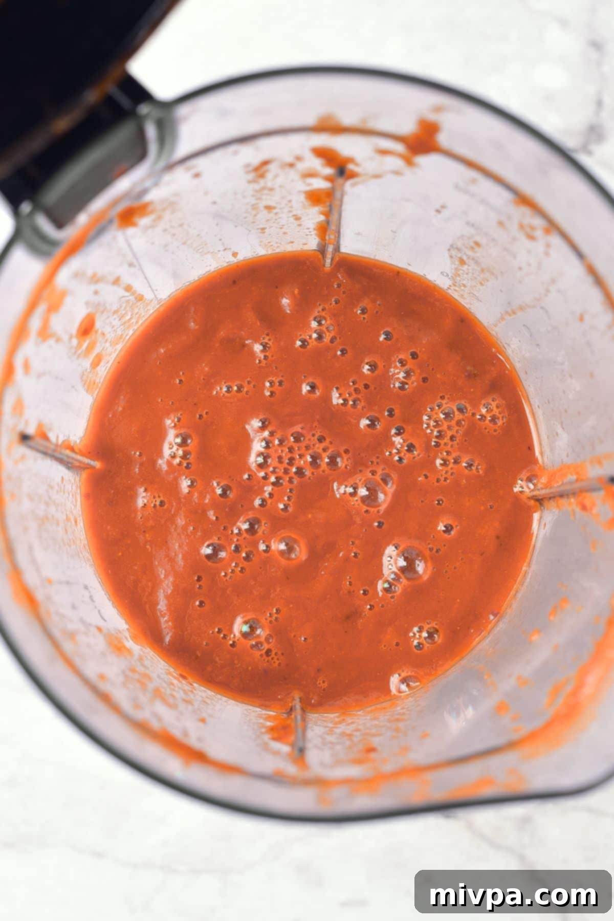 Smooth red liquid mixture in a blender, ready to become the birria sauce.