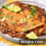 A plate of birria tacos with lime wedges and a small bowl of consomé.