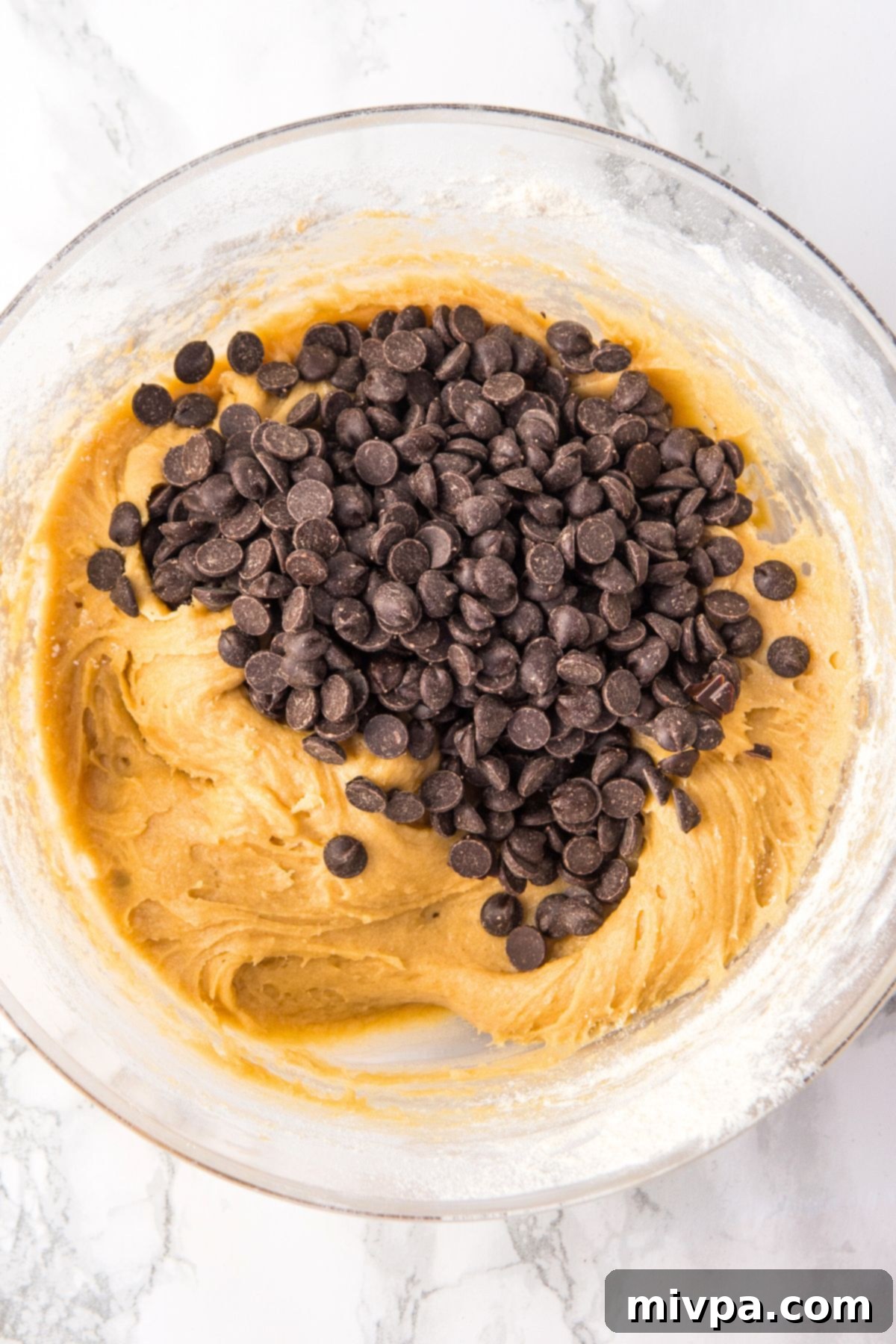 Gluten-Free Chocolate Chip Cookie Bars (Dairy-Free) - Add Chips Dairy-free chocolate chips resting on top of the cookie dough, ready to be folded in.