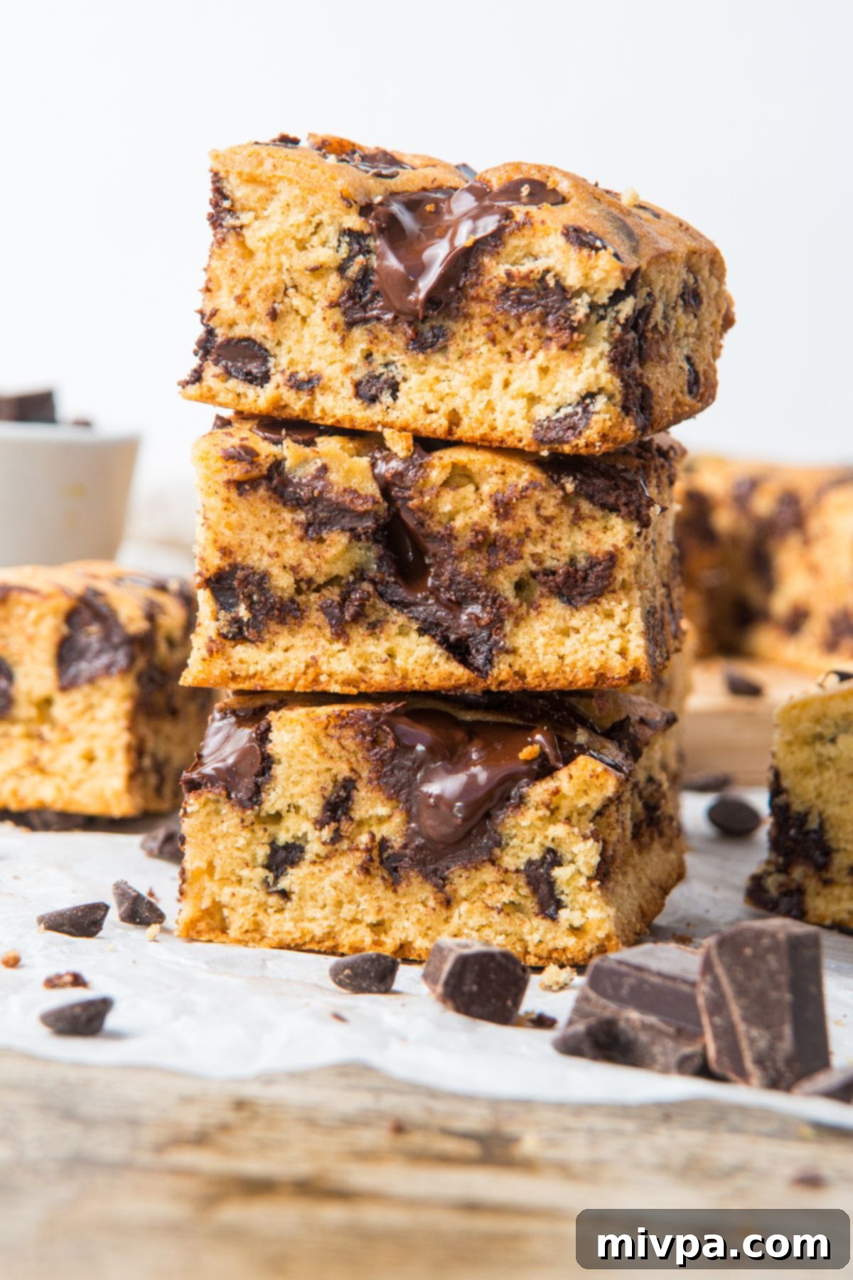 Gluten-Free Chocolate Chip Bars (Dairy-Free) Stack A tall stack of golden-brown gluten-free chocolate chip cookie bars on parchment paper, showcasing their thick, chewy texture.