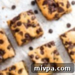 Chewy Gluten and Dairy Free Chocolate Chip Cookie Bars 2 Gluten-free chocolate chip cookie bars on parchment paper, fresh out of the oven.