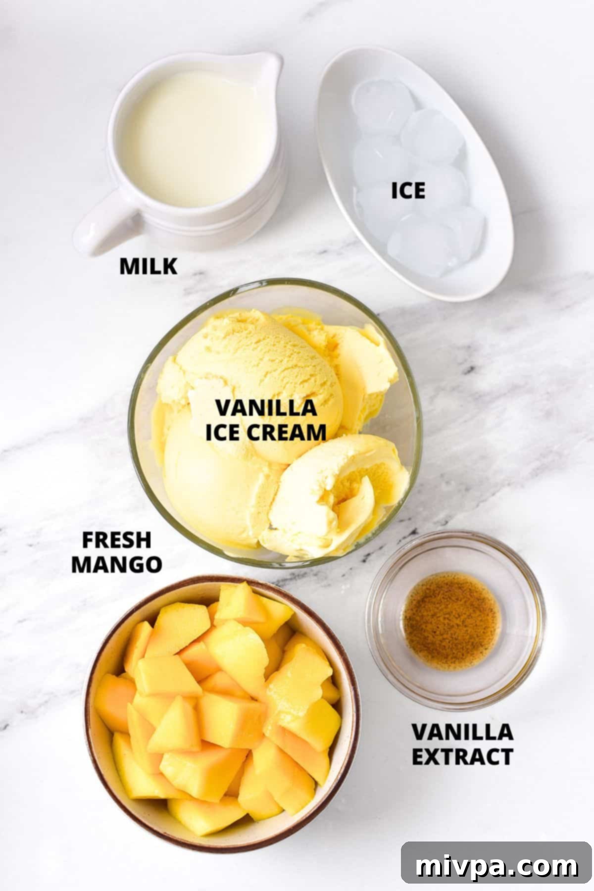 5-Ingredient Creamy Mango Milkshake Recipe Ingredients for creamy mango milkshake recipe laid out on a stylish marble board, featuring fresh mango, ice cream, milk, vanilla, and ice.
