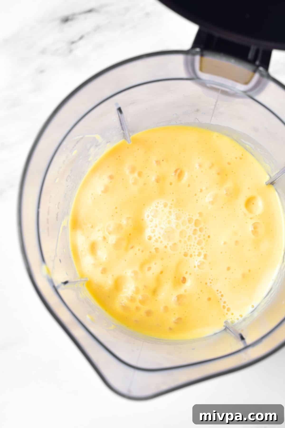 Mango Milkshake Recipe Blended mango shake in a blender, showing a smooth, creamy texture.