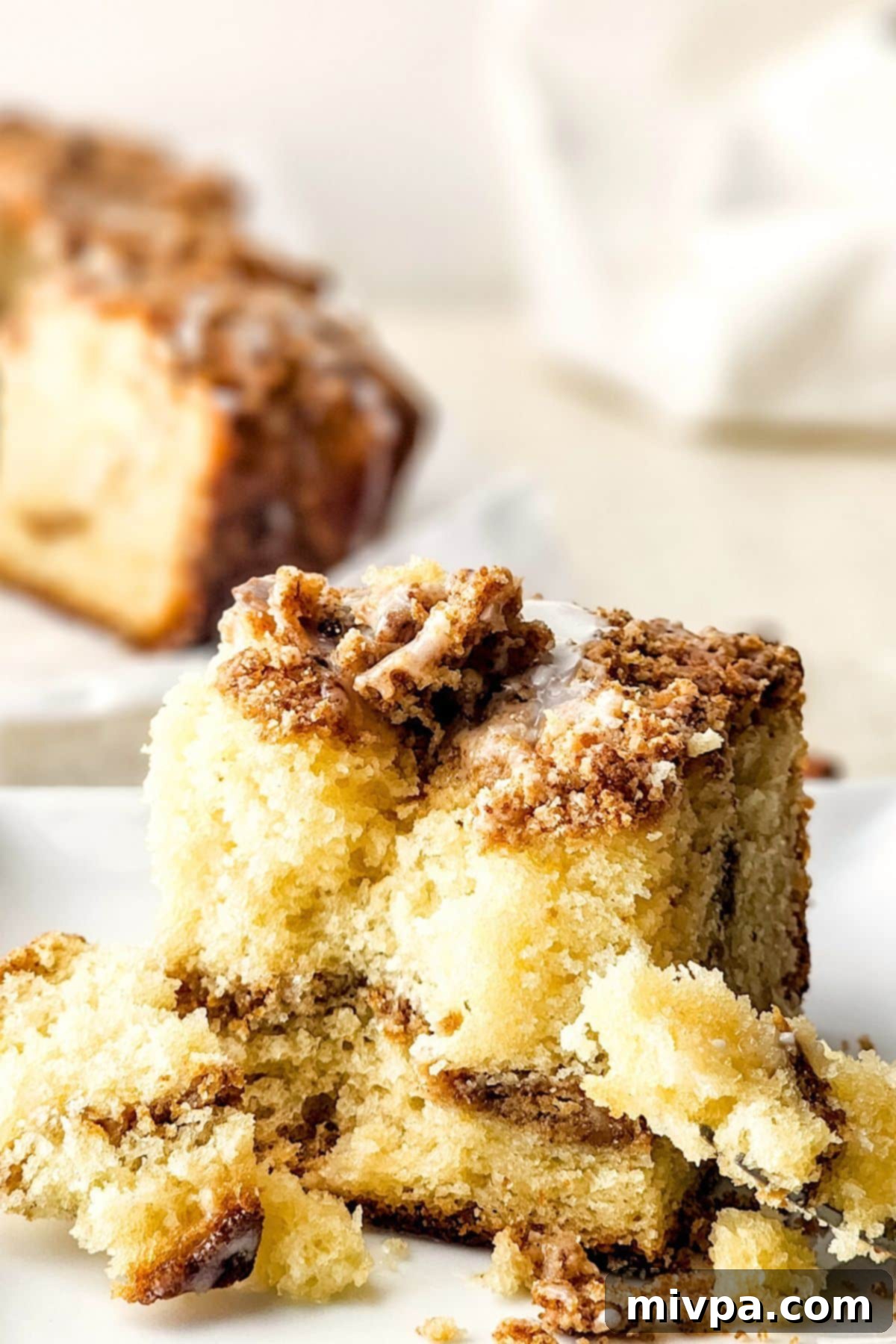 Gluten-Free Cinnamon Crumb Cake Slice A half-eaten piece of gluten-free cinnamon crumb cake, showing the moist cake, crisp streusel, and a hint of the drizzled glaze.