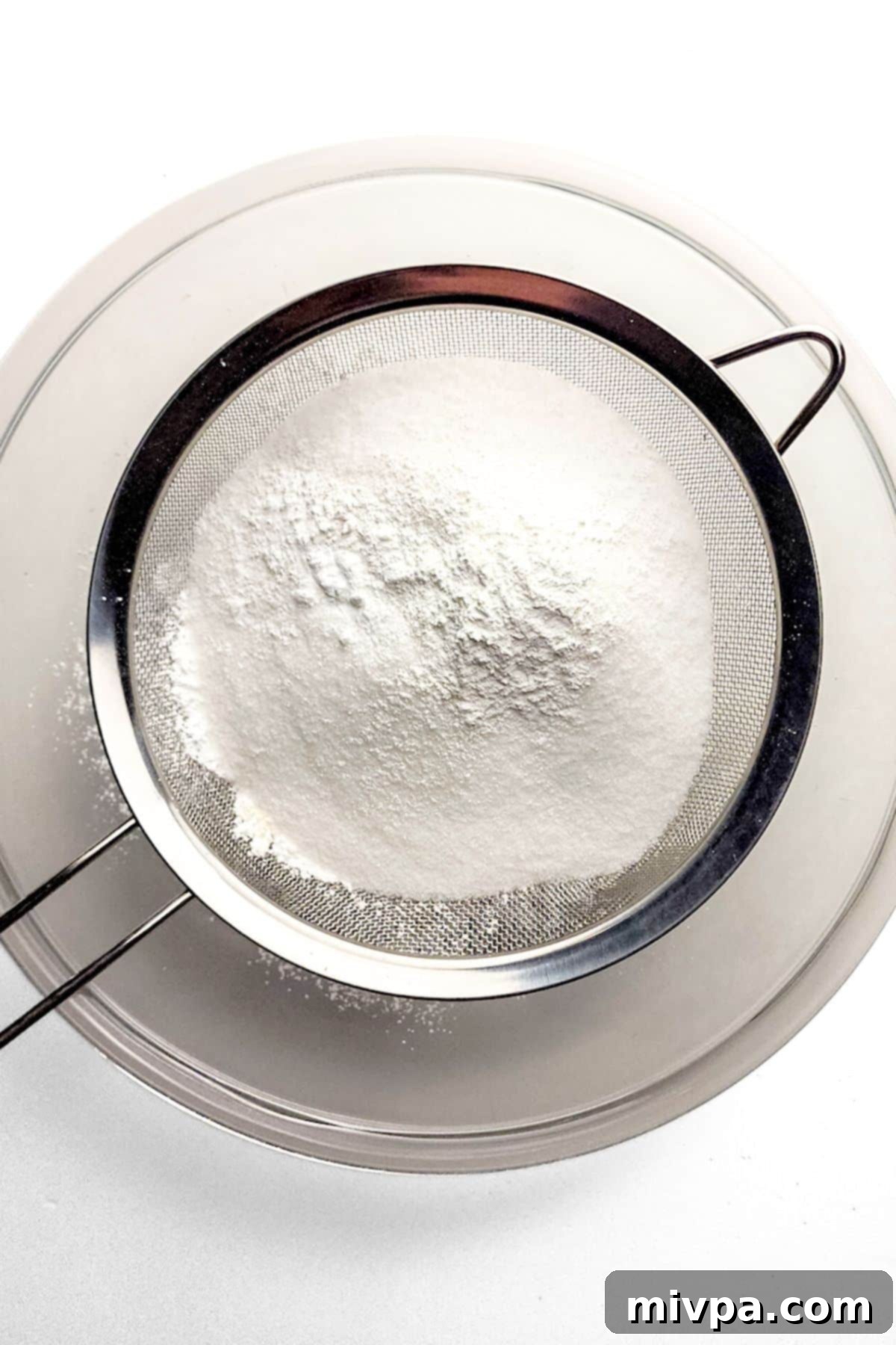 Sifting Dry Ingredients for Gluten-Free Crumb Cake Sifting gluten-free flour, baking powder, baking soda, salt, and sugar into a large mixing bowl.