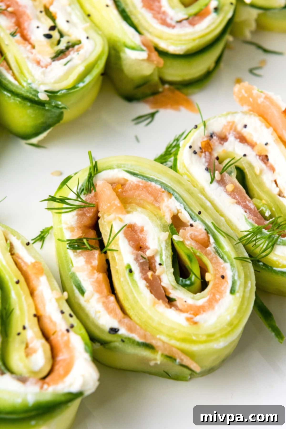 Easy Cucumber Roll Ups Up close shot of salmon cucumber roll ups topped with dill.