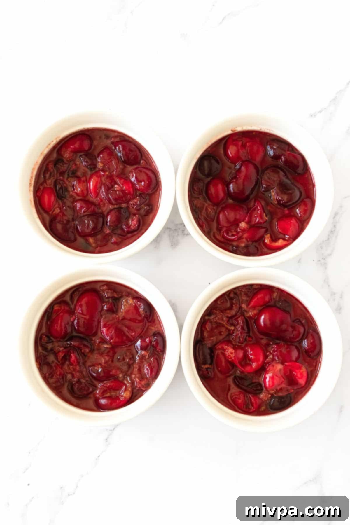 Cherry Crumble Recipe Individual ramekins filled with vibrant fresh cherry filling, glistening and ready for the crumble topping.