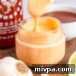 Holding up a spoonful of sriracha aioli from a jar