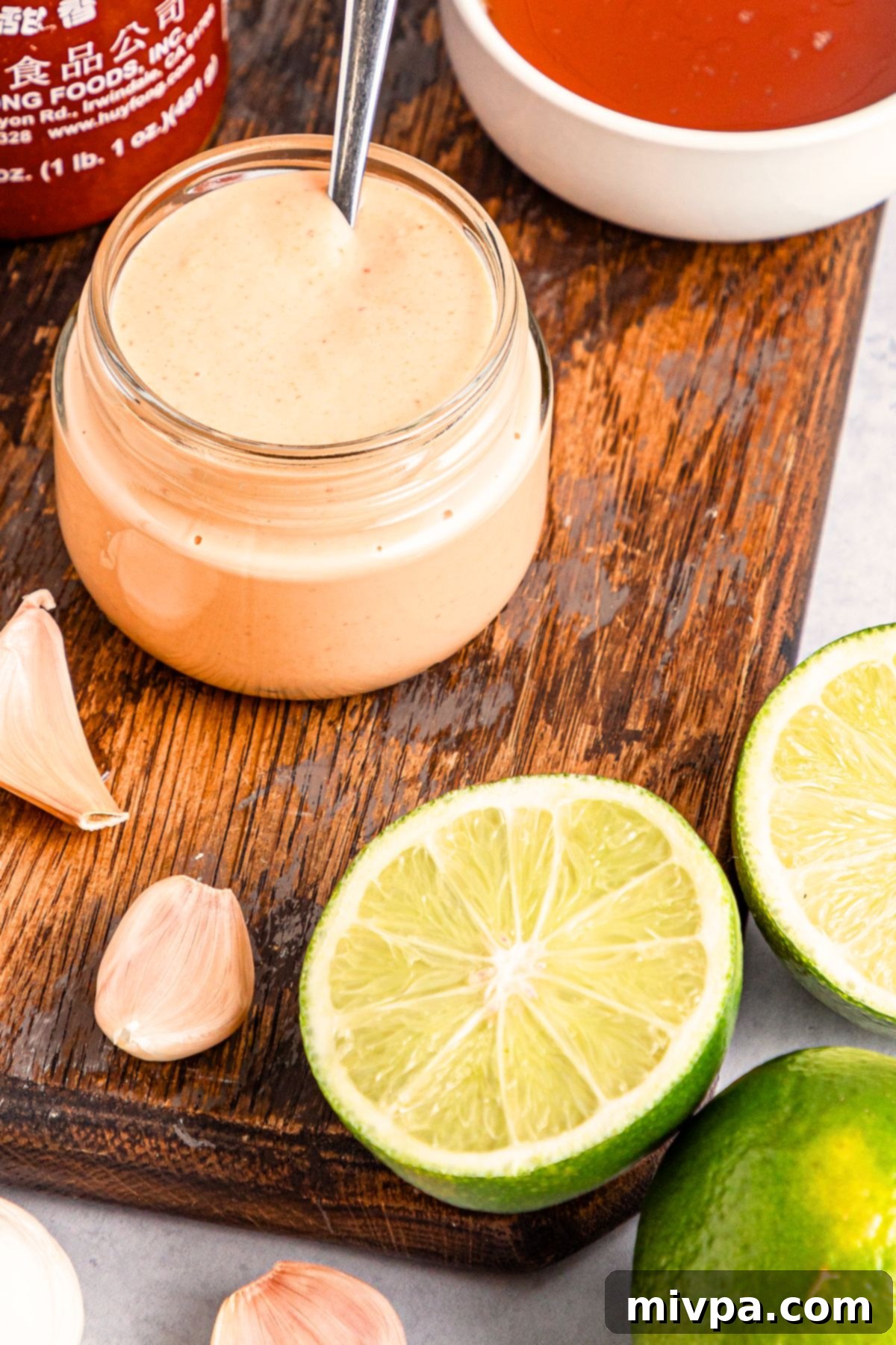 A jar of homemade sriracha aioli on wooden board.