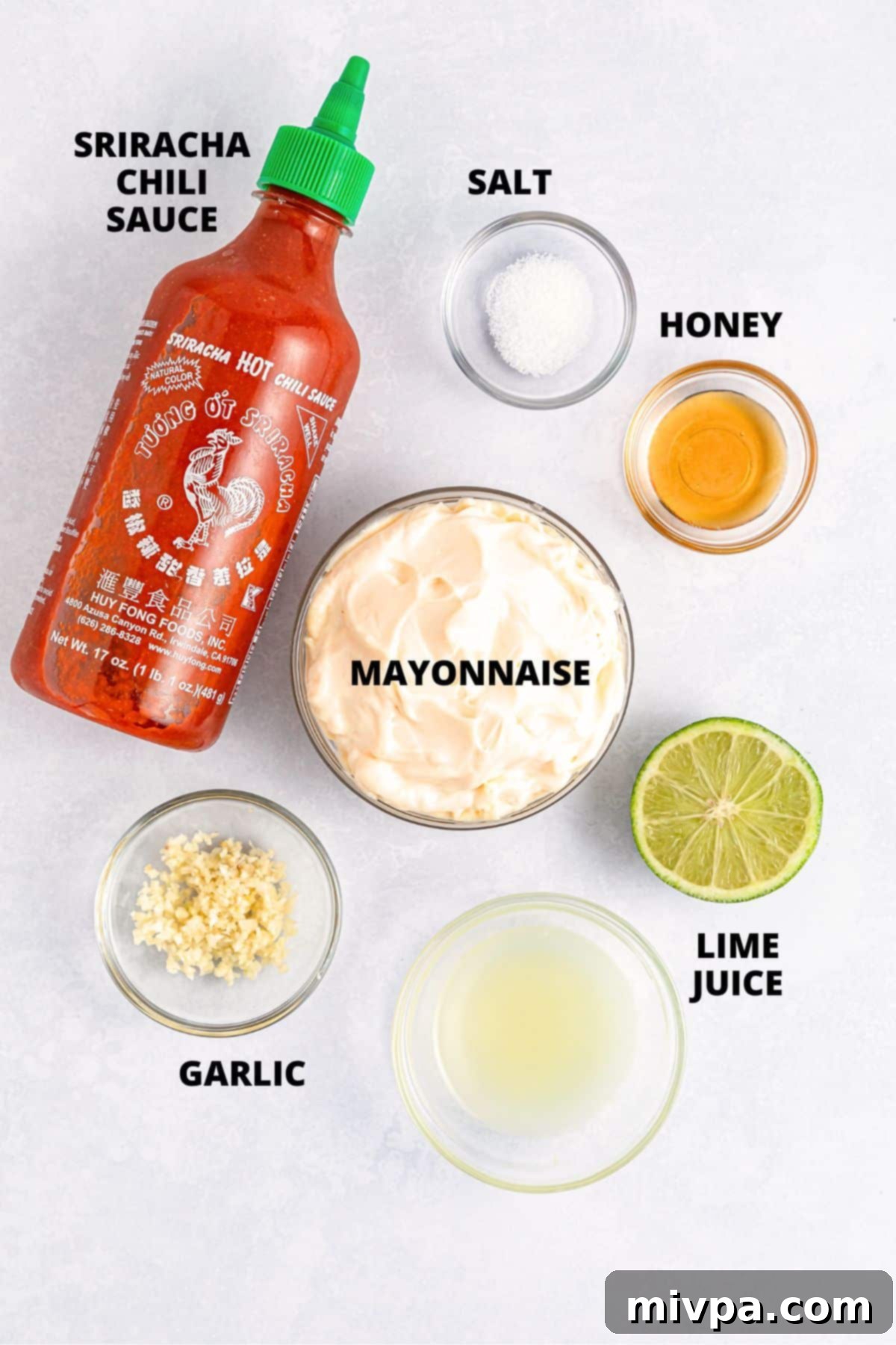 Ingredients for sriracha aioli recipe laid out on white board.