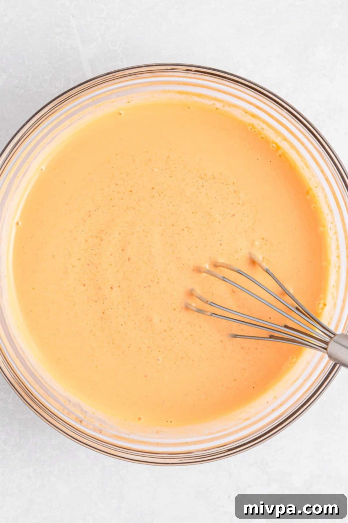 Whisking sriracha aioli in glass bowl.