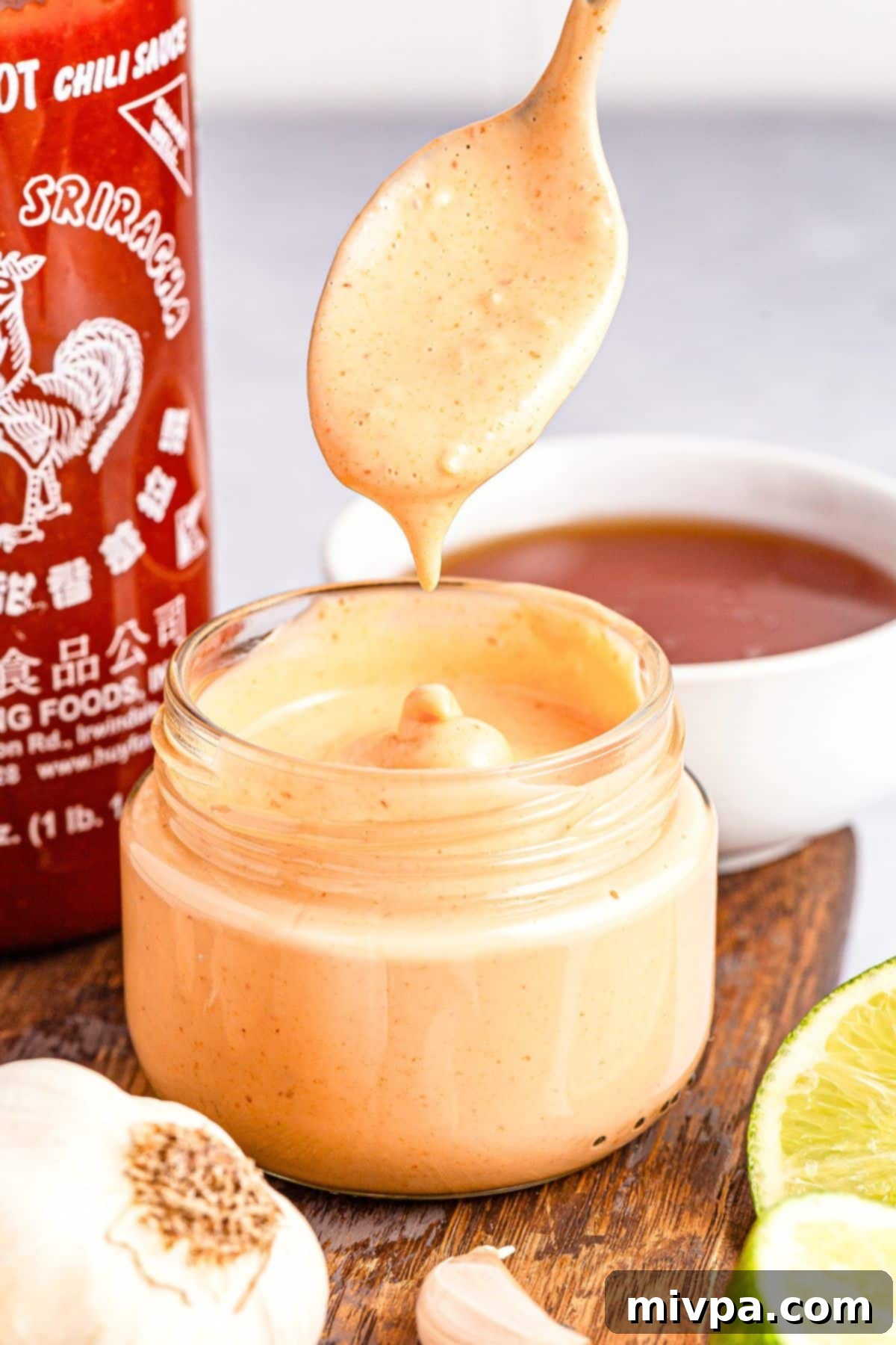 Drizzling sriracha aioli into a jar.