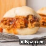 A gluten-free pulled pork sandwich on parchment paper.