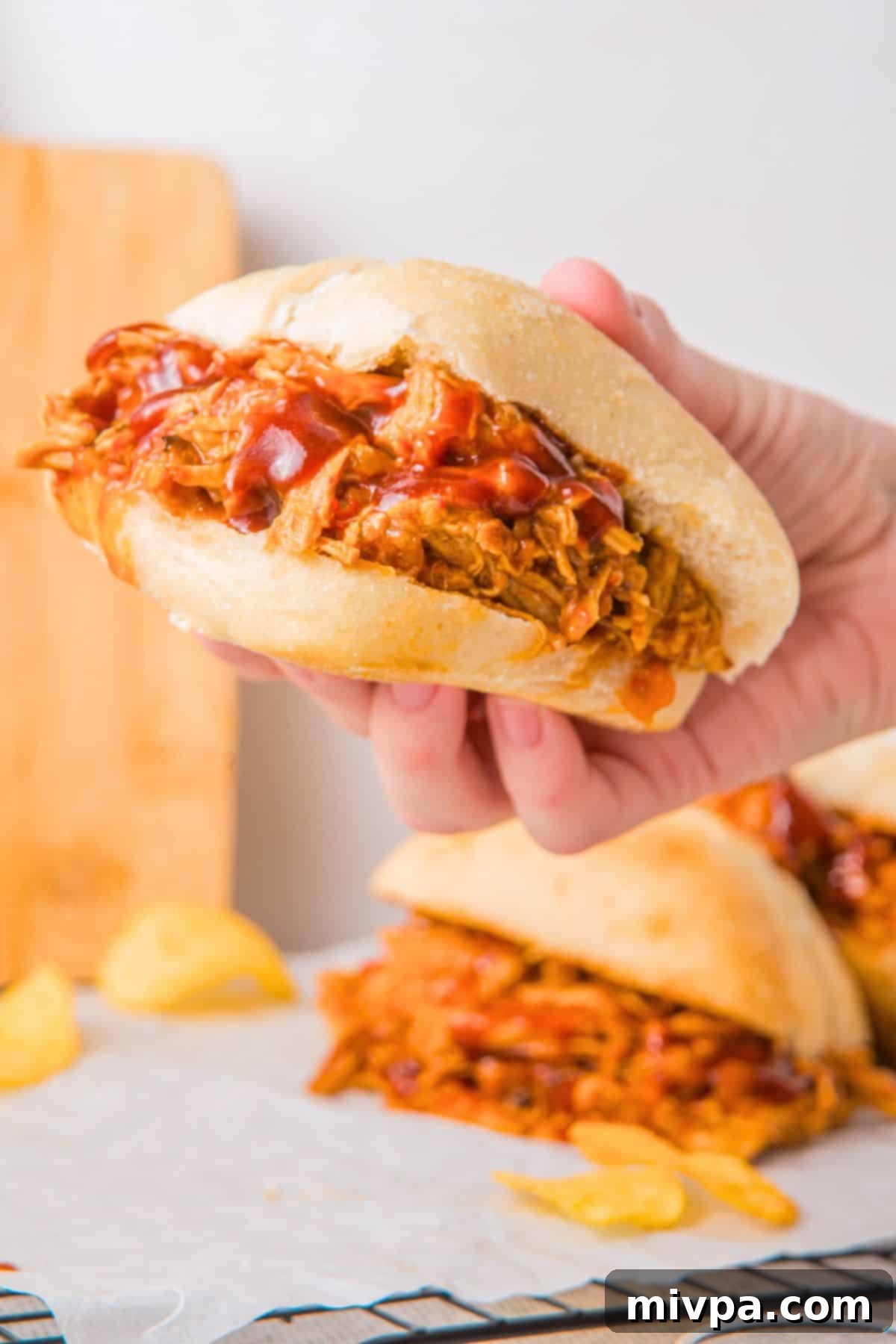 Holding up a stovetop pulled pork sandwich.