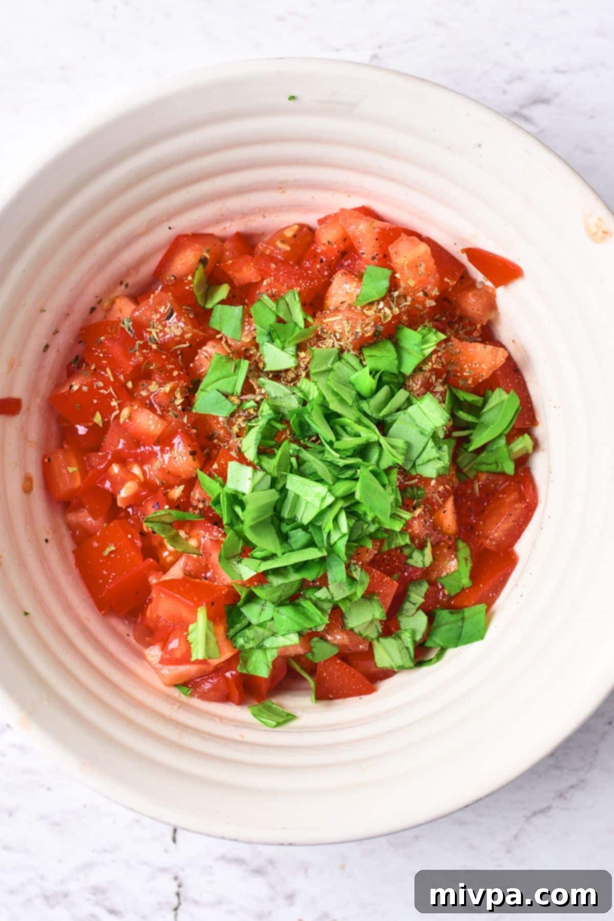 Tomato Basil Bruschetta (Gluten-Free, Vegan) A bowl with diced tomatoes and chopped fresh basil.