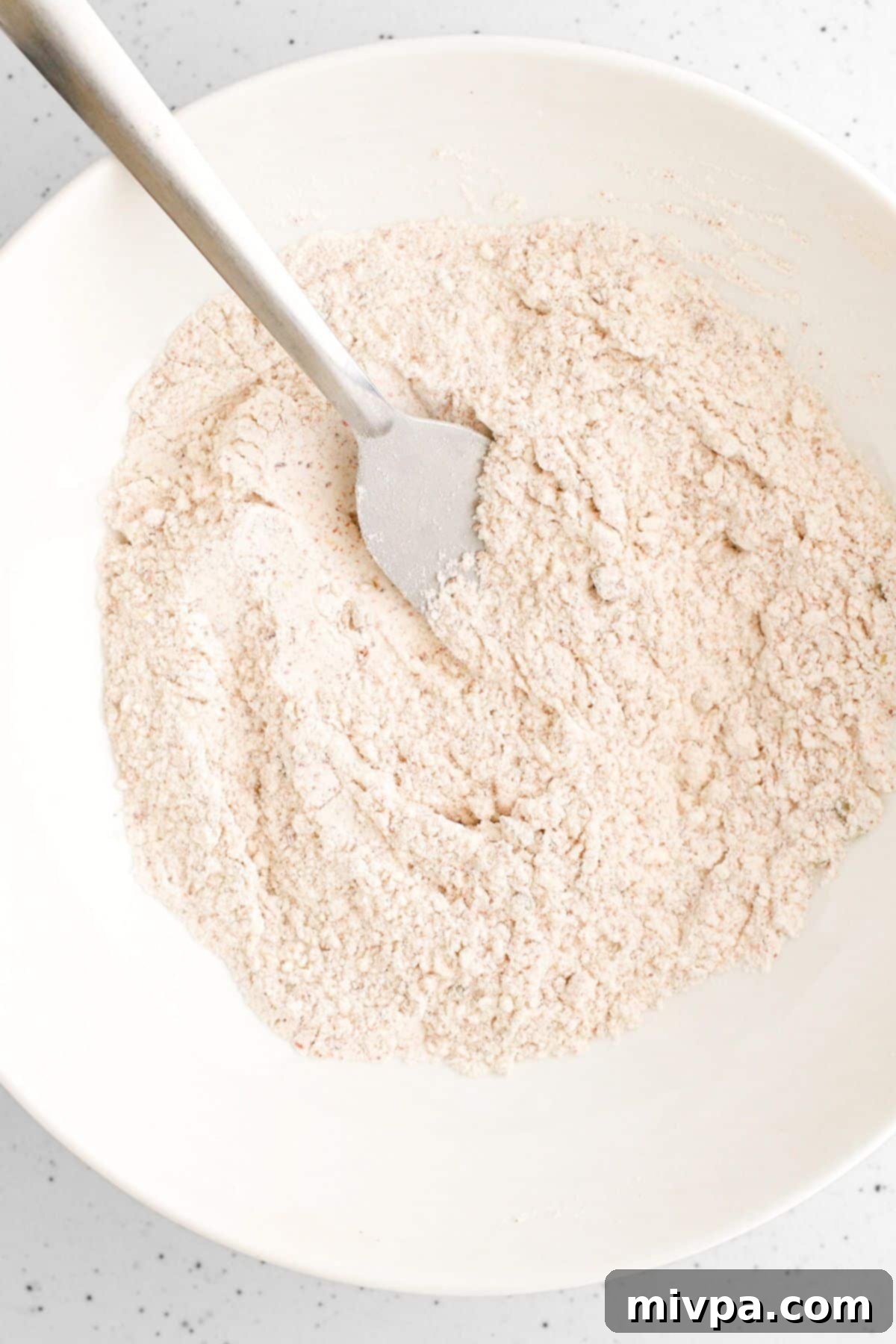 Whisking flour mixture in white bowl.