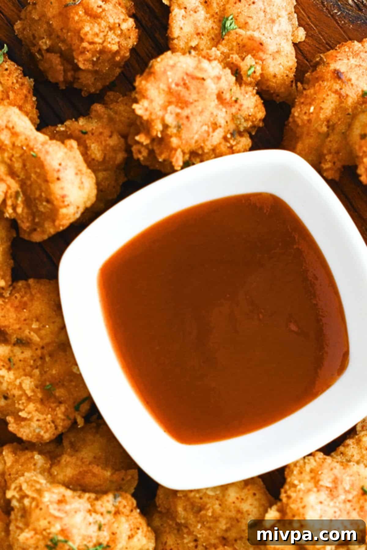 Popcorn chicken and a small bowl of chili sauce.