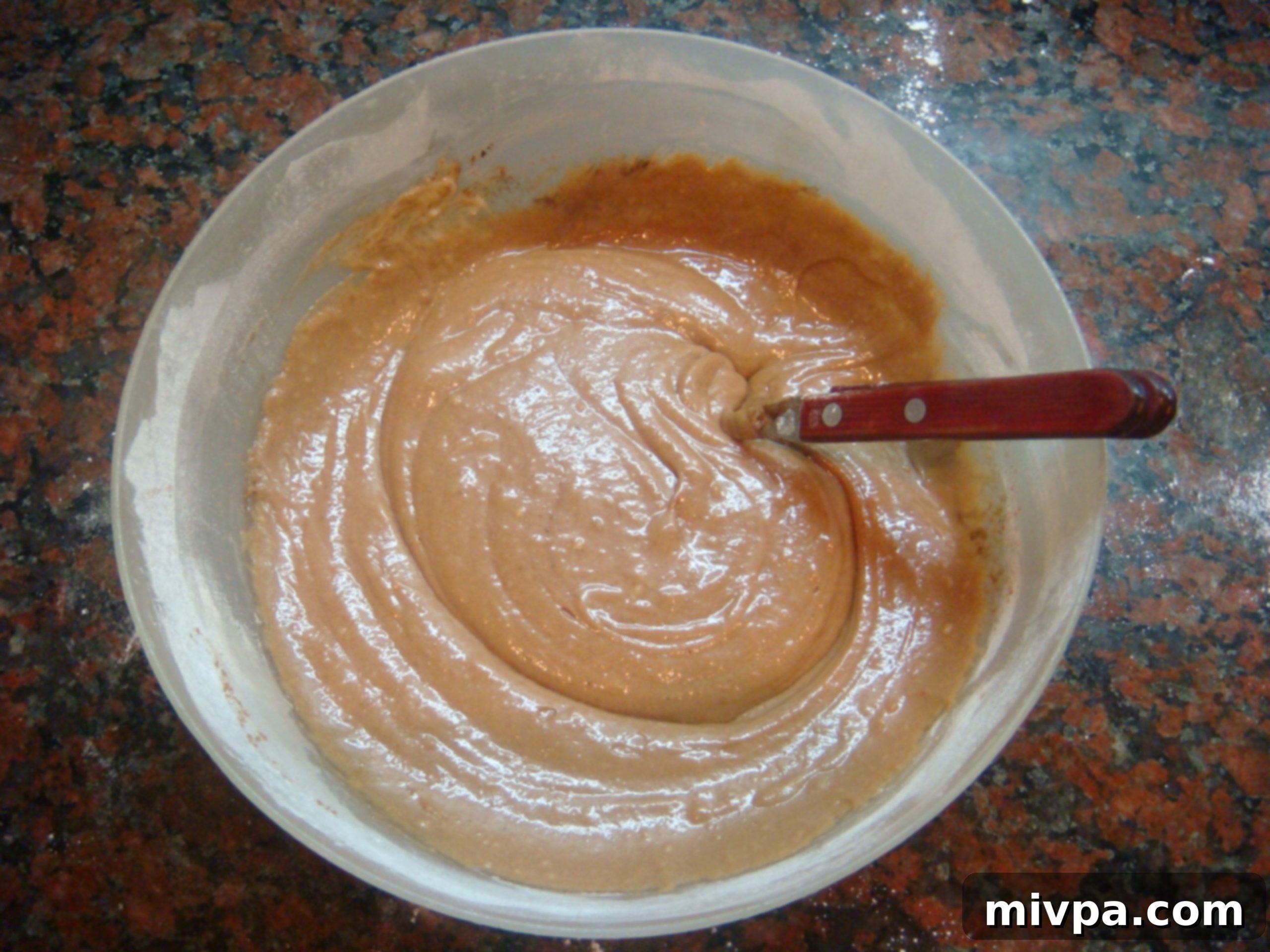 The fully mixed muffin batter, showcasing its rich chocolate color and smooth, thick texture, ready for portioning.