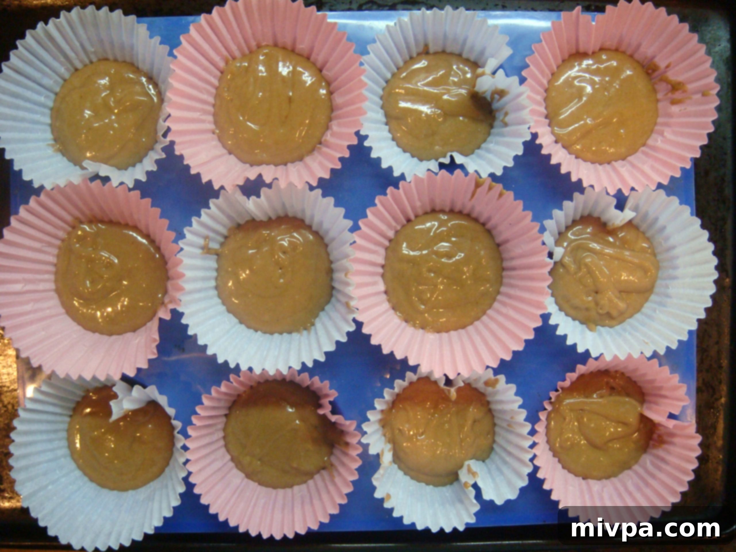 Muffin cups being filled approximately one-quarter full with the chocolate batter, ready for the cherry layer.