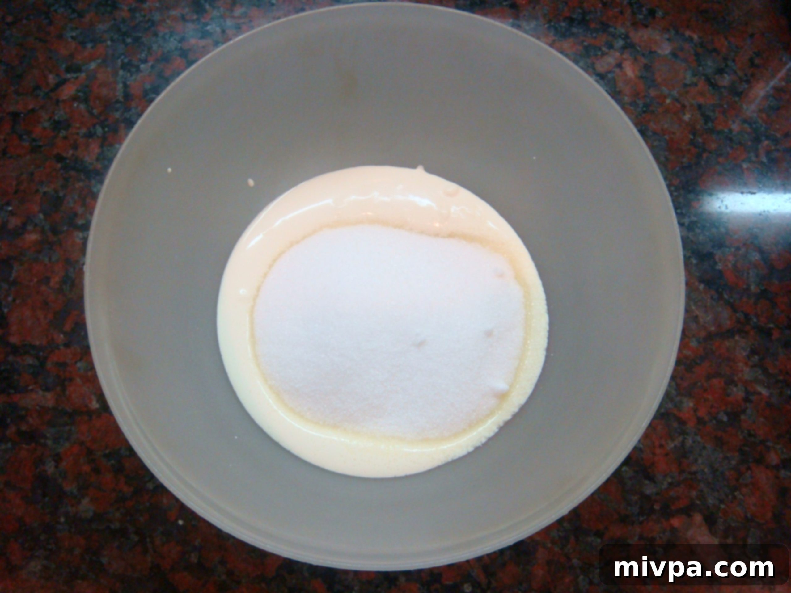 A mixing bowl where milk cream and granulated sugar are being vigorously combined, starting the muffin batter.