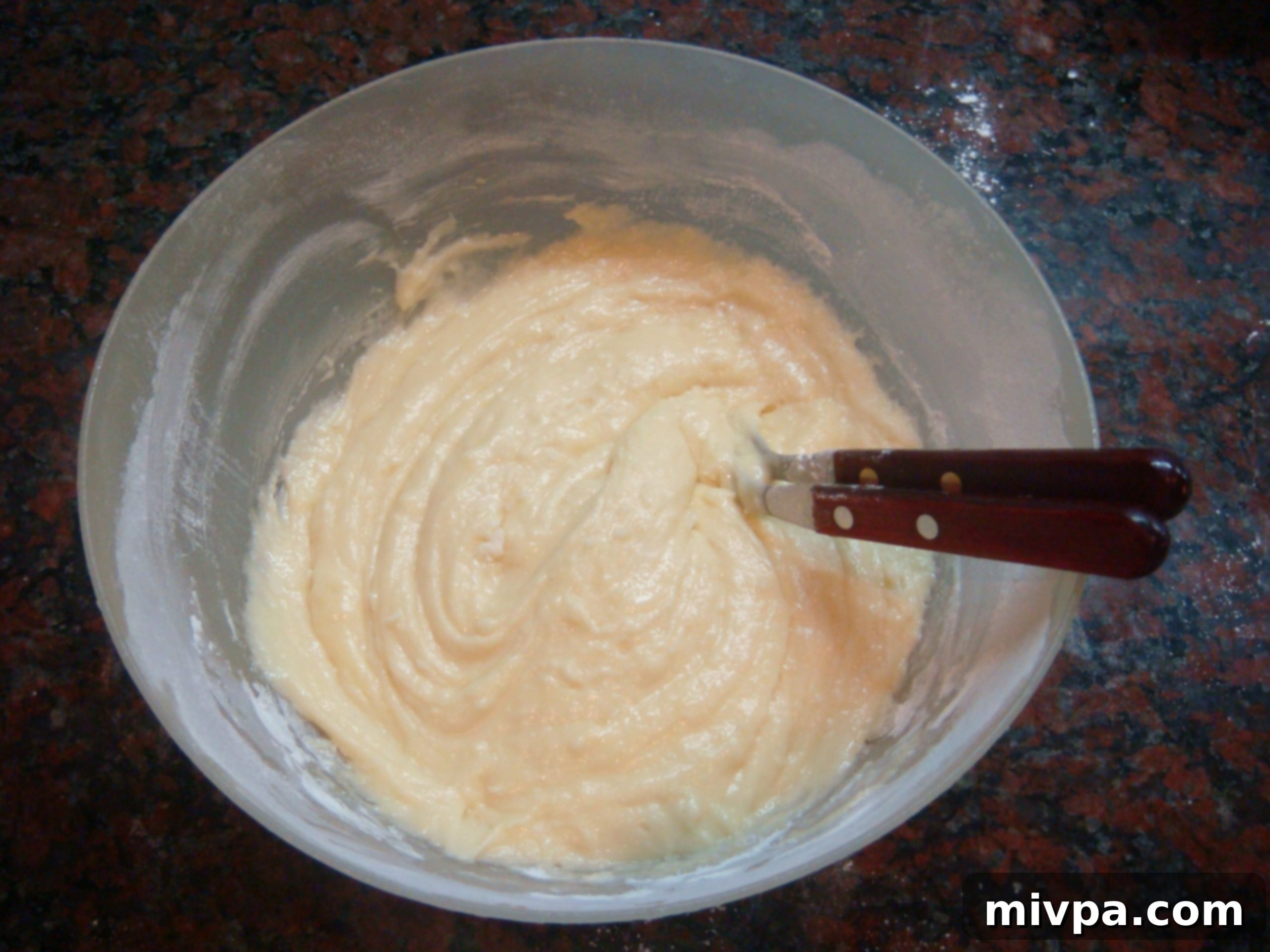 The muffin batter after thoroughly mixing, displaying a smooth, homogenous consistency without any visible lumps.