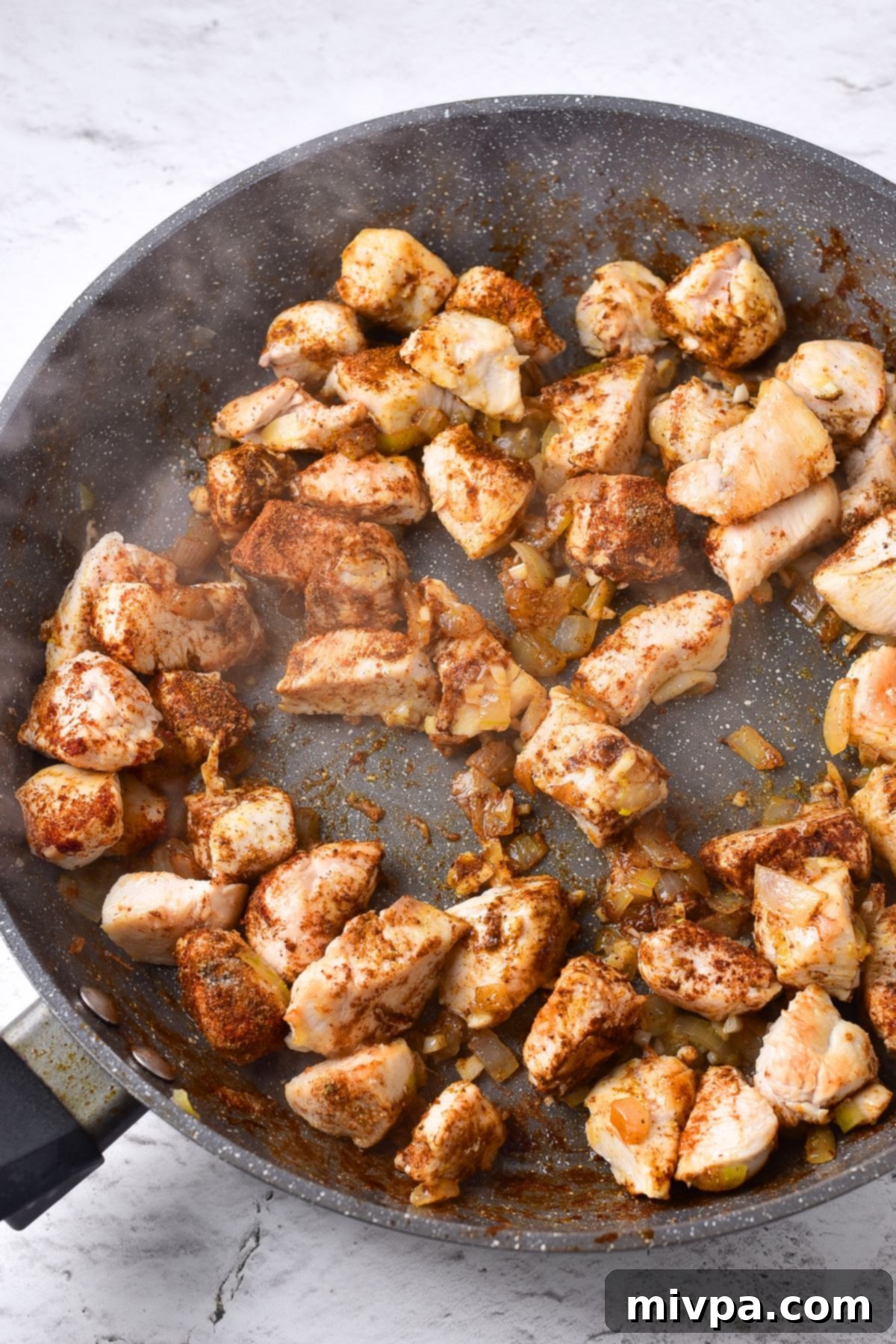 Cooking cubed chicken, onions, garlic and ginger and spices in skillet.