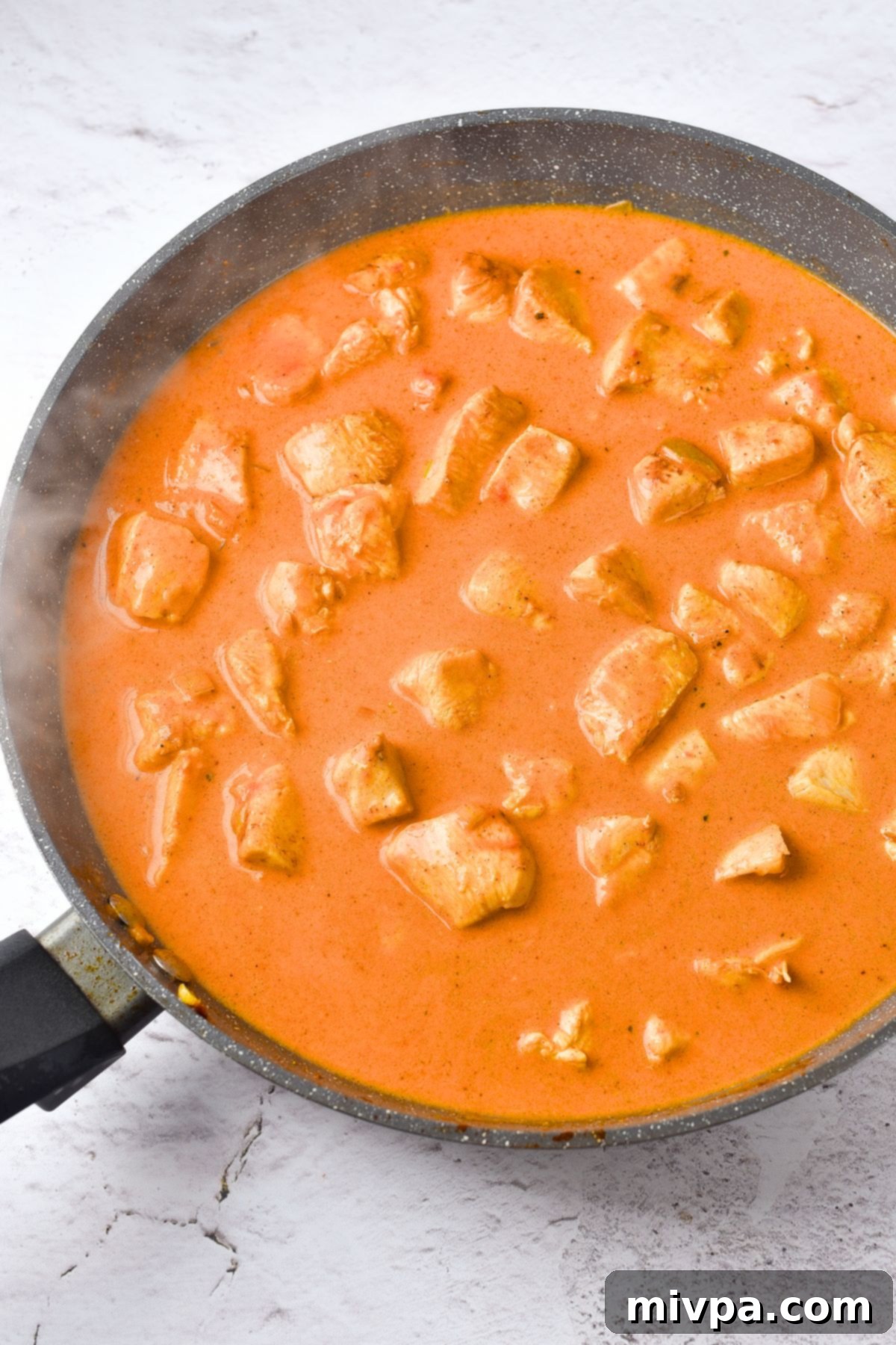 Top down view of a skillet with gluten-free curry chicken.