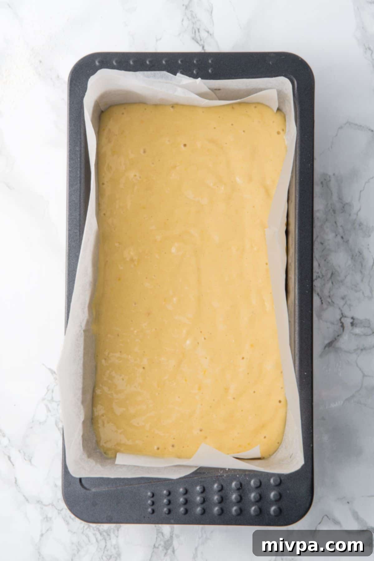 Gluten Dairy-Free Lemon Drizzle Cake Cake batter poured into a parchment-lined loaf pan, ready for baking.