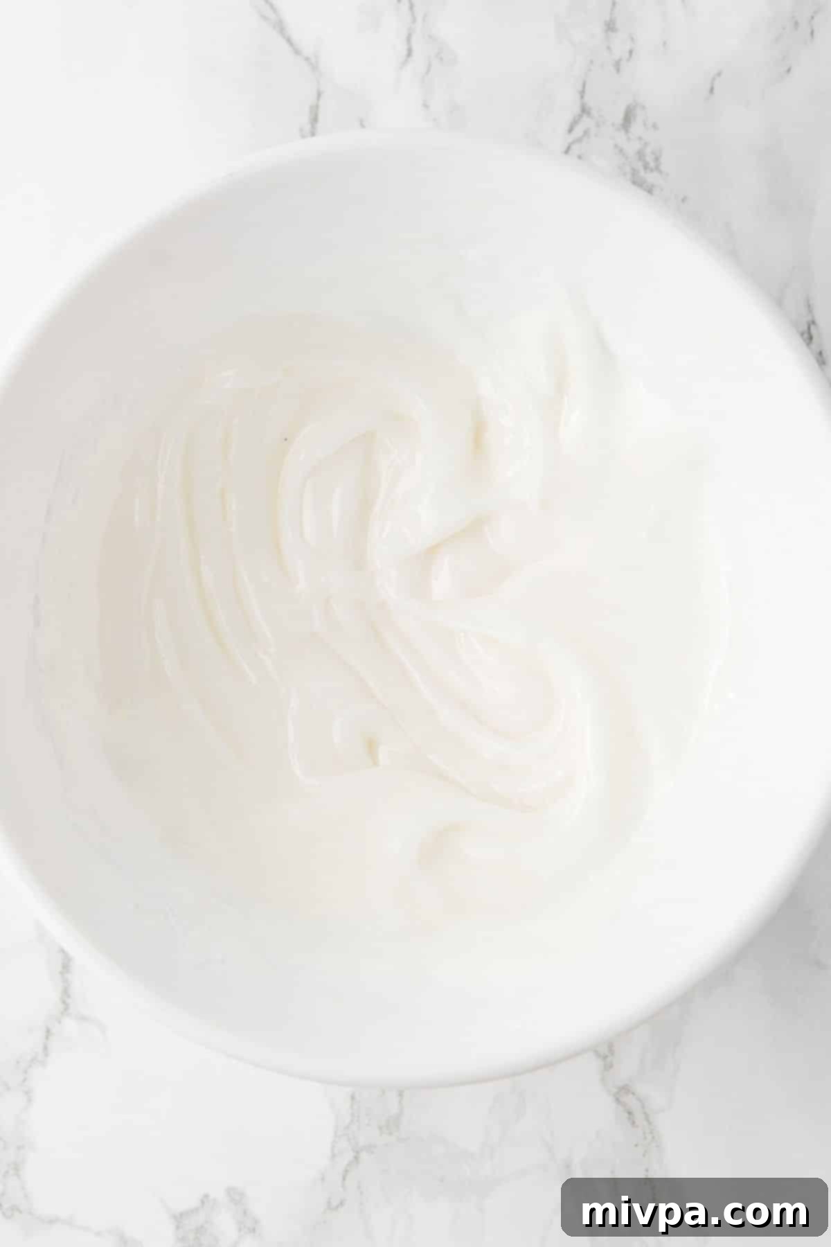 Lemon Cake with Lemon Glaze Smooth, white lemon glaze in a small bowl, ready for drizzling.