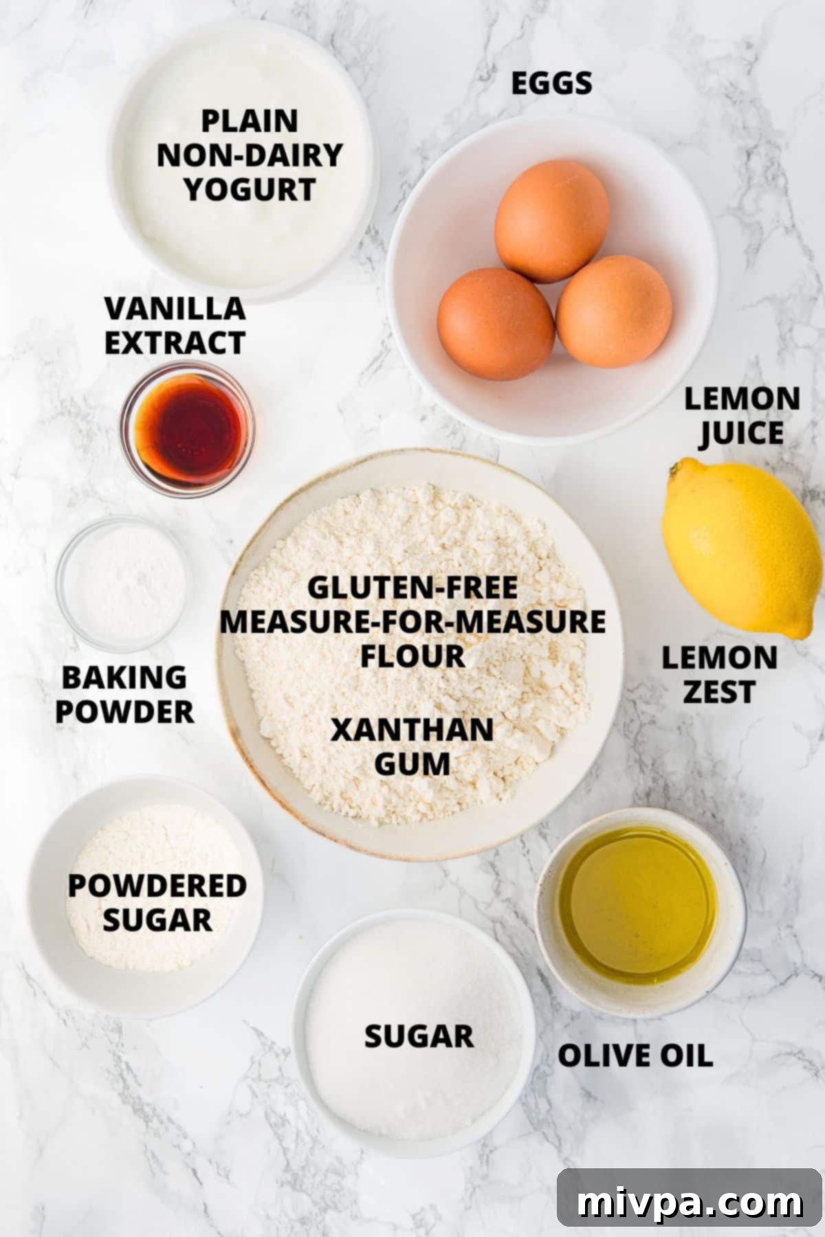 Gluten-Free Lemon Drizzle Cake Ingredients (Dairy-Free) All the fresh ingredients for gluten-free lemon drizzle cake recipe neatly laid out on a clean marble board.