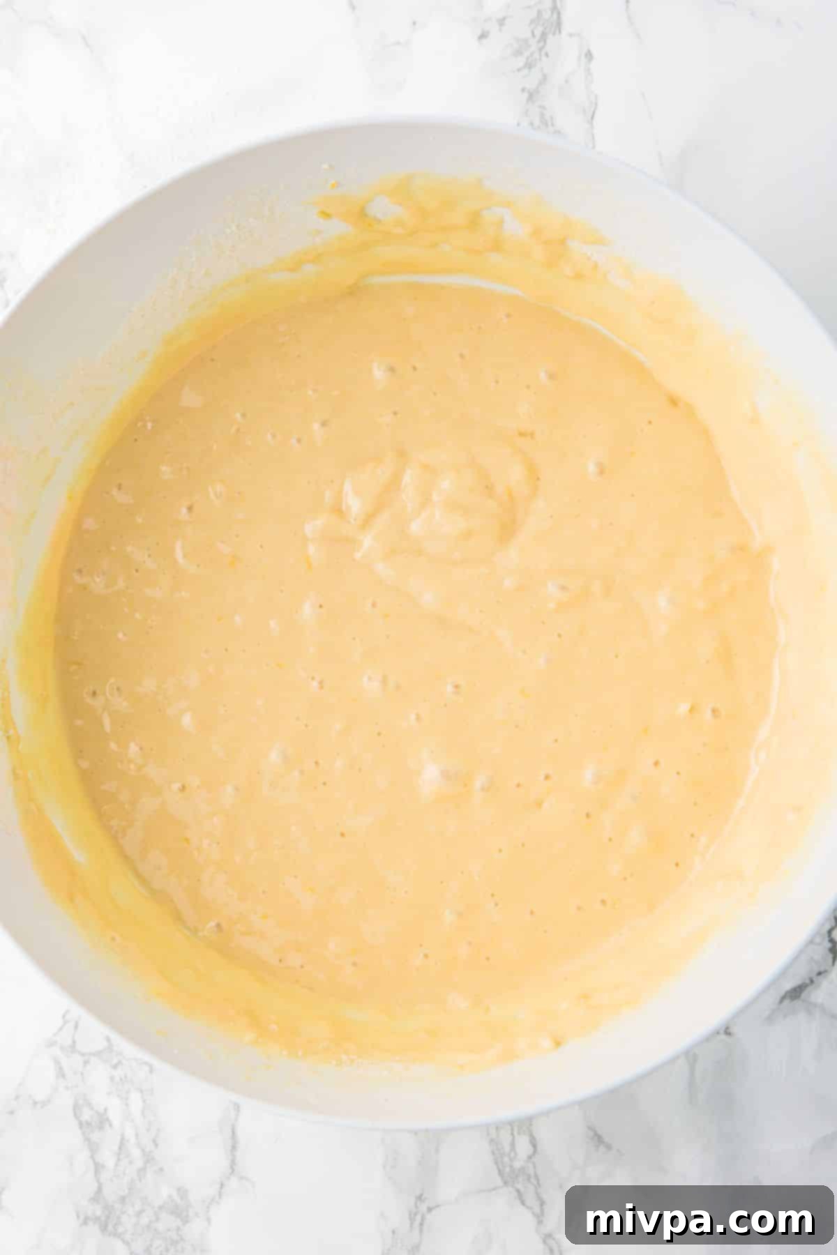 Lemon Drizzle Cake (Gluten-Free, Dairy-Free) Thick yellow cake batter in a mixing bowl, showing a smooth consistency.