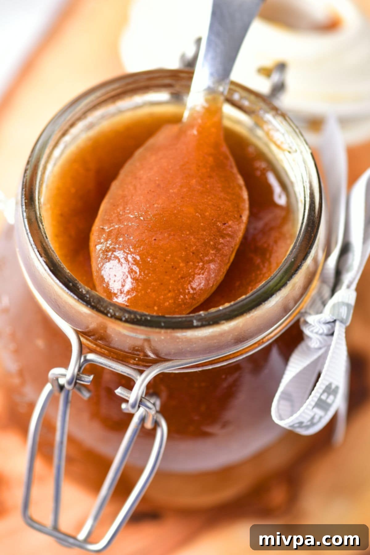 Holding up a spoonful of apple butter from a jar.