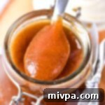 Holding up a spoonful of apple butter from a jar