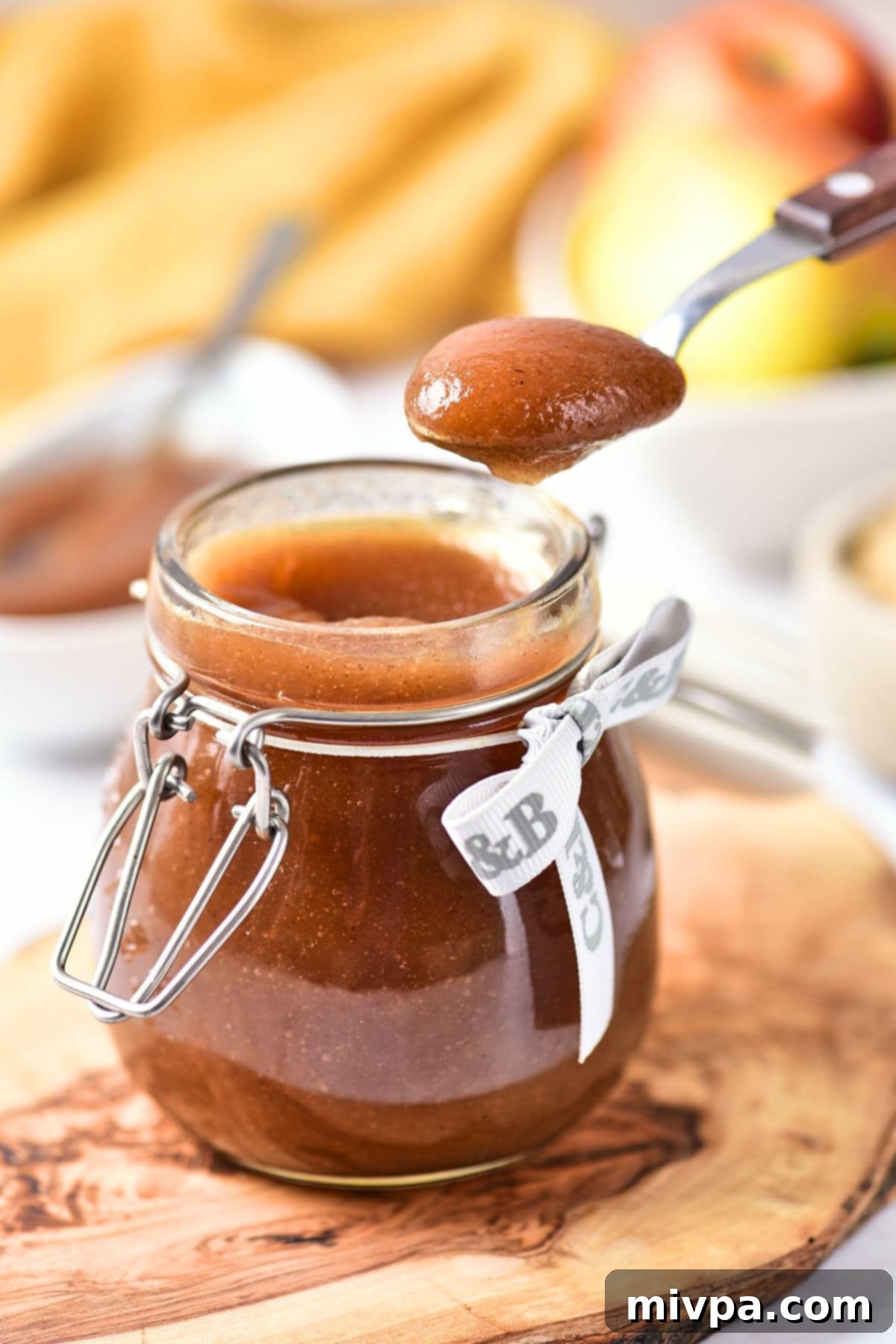 Holding up a a spoonful of homemade apple butter from a jar