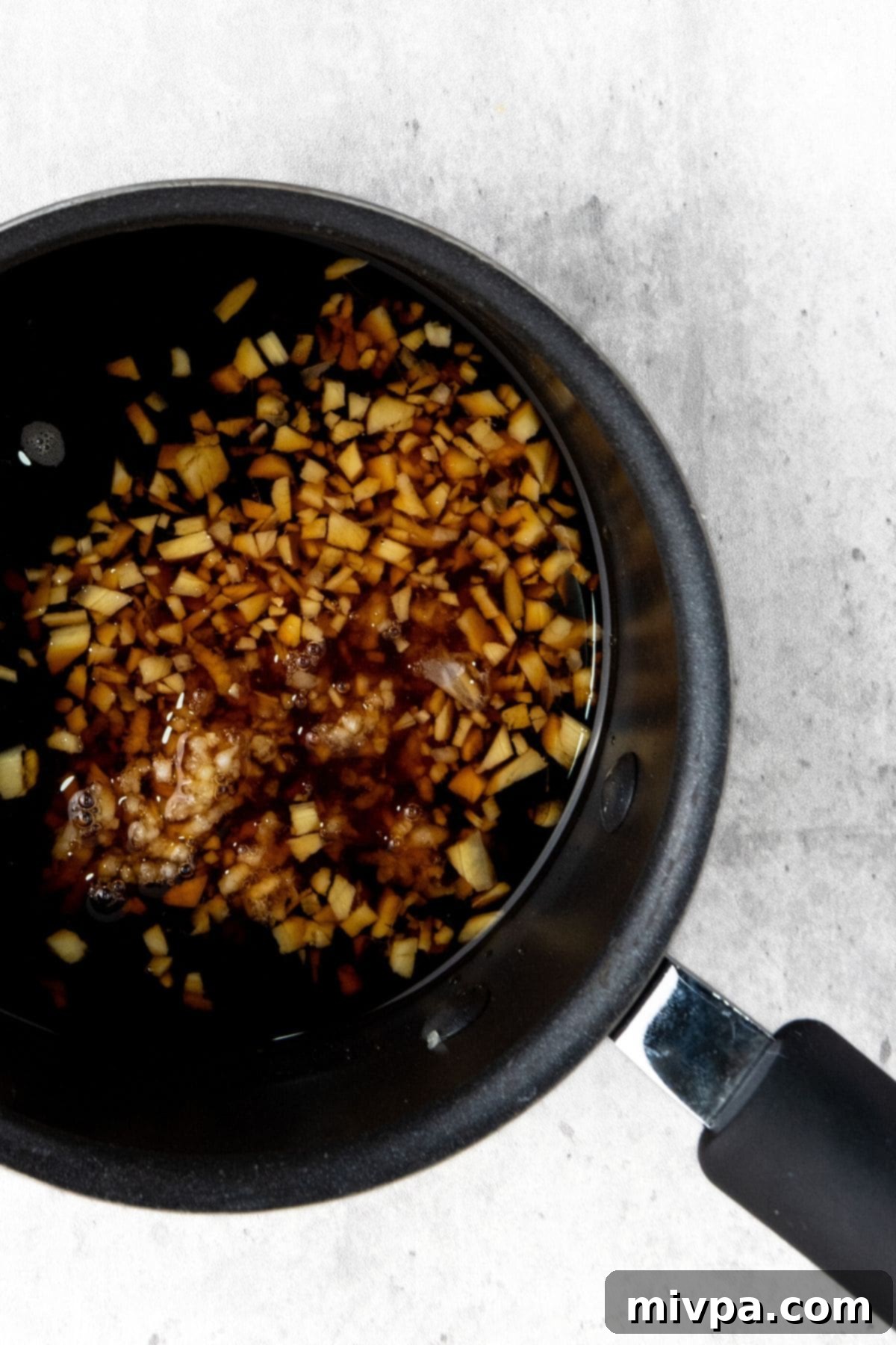 Close-up photo of a saucepan on the stove, showing the preparation of homemade gluten-free teriyaki sauce, bubbling gently and thickening to a glossy consistency.