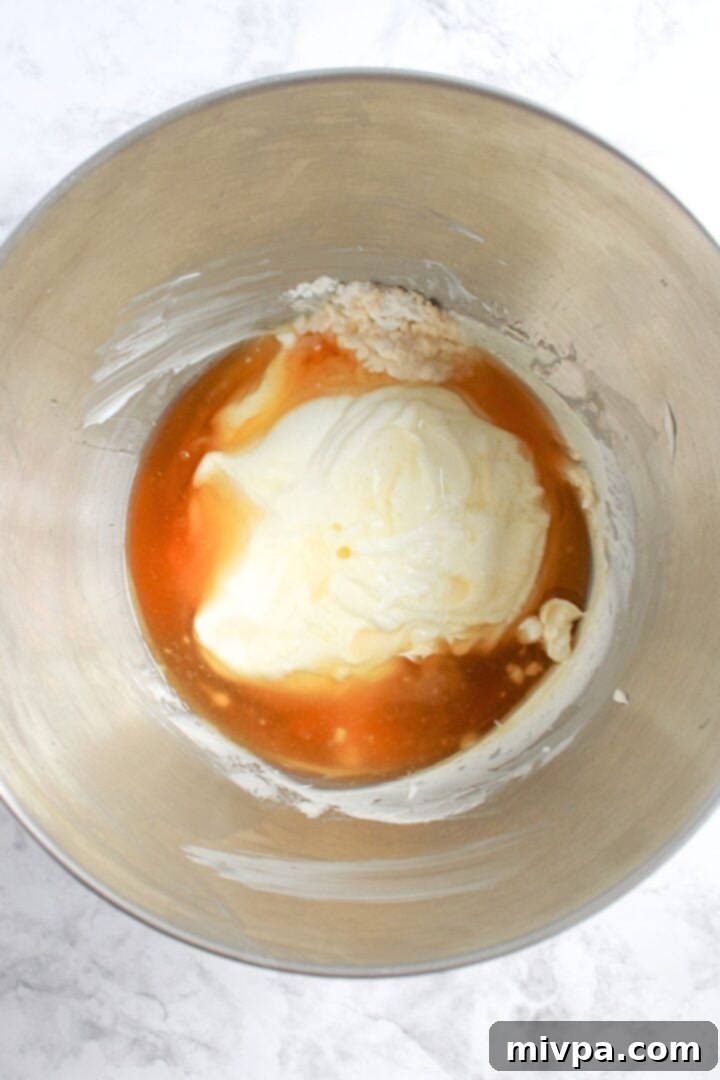 The smooth, creamy mixture of honey, vanilla, Greek yogurt, and cream cheese in a mixing bowl.
