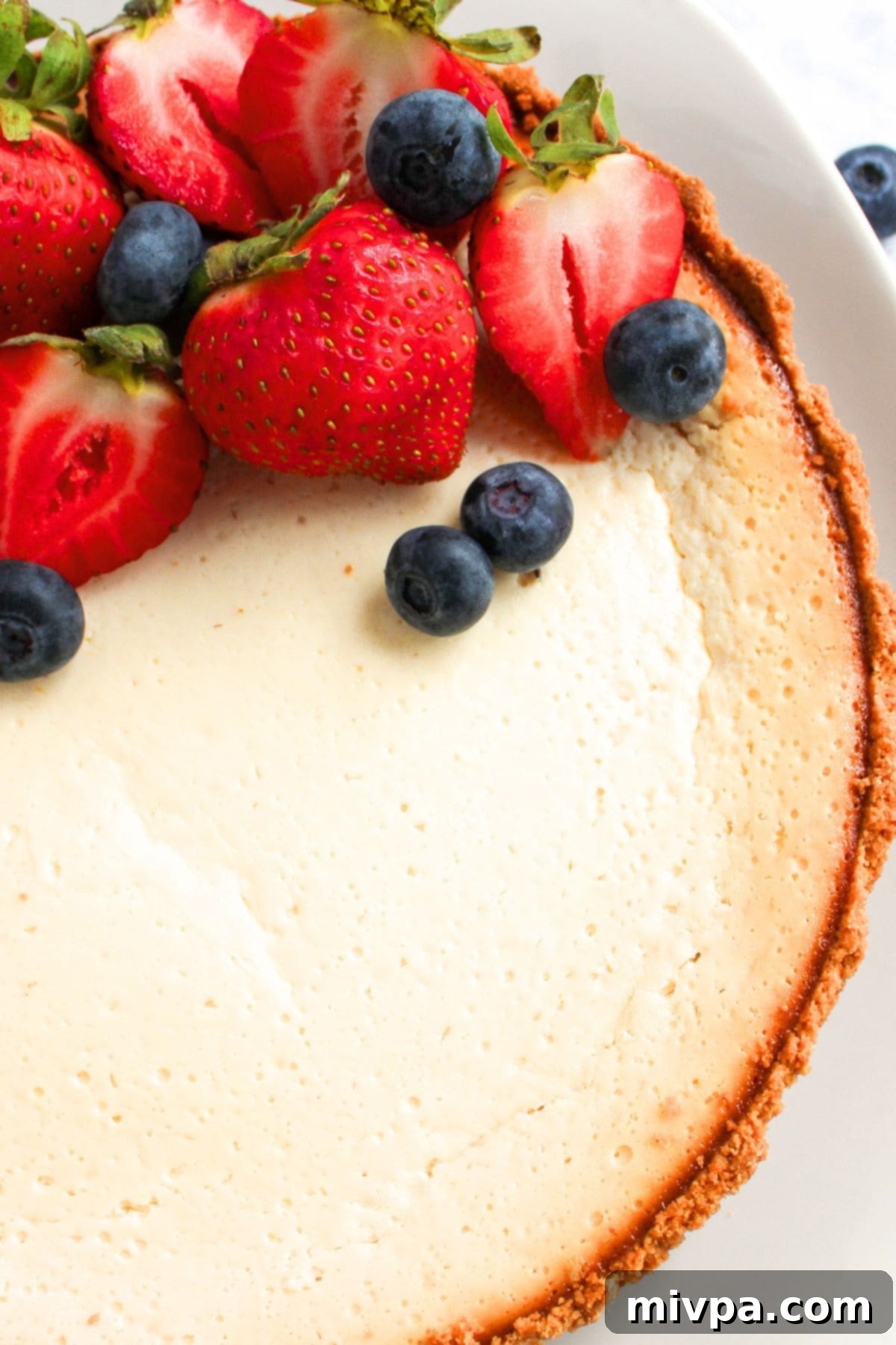Top-down view of a stunning Greek yogurt cheesecake generously topped with an assortment of fresh berries.