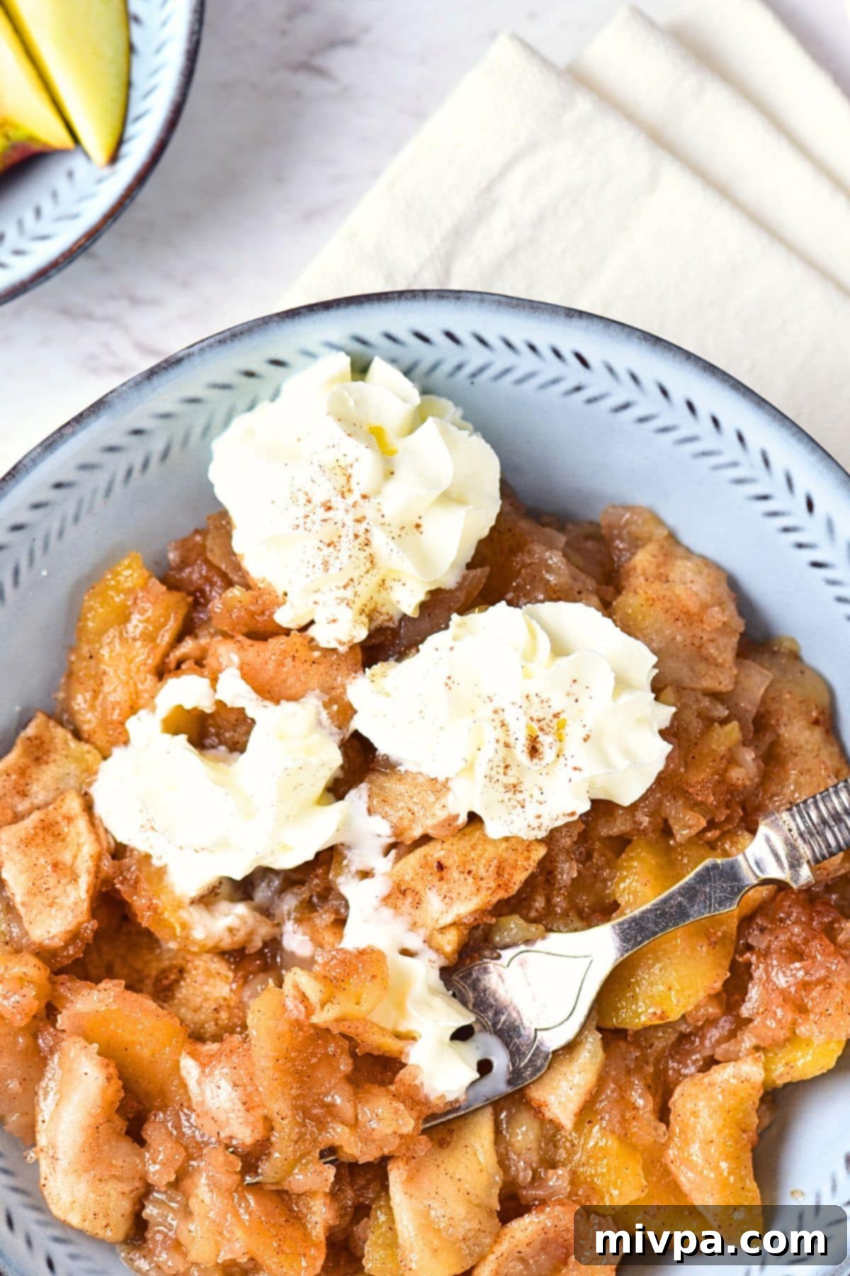 Top down view of a fork in a bowl of healthy baked apples.