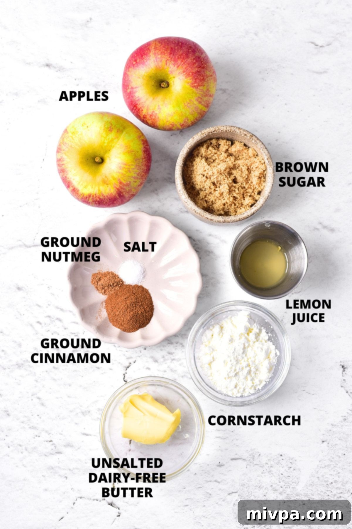 Ingredients for baked apples recipe laid out on marble board.