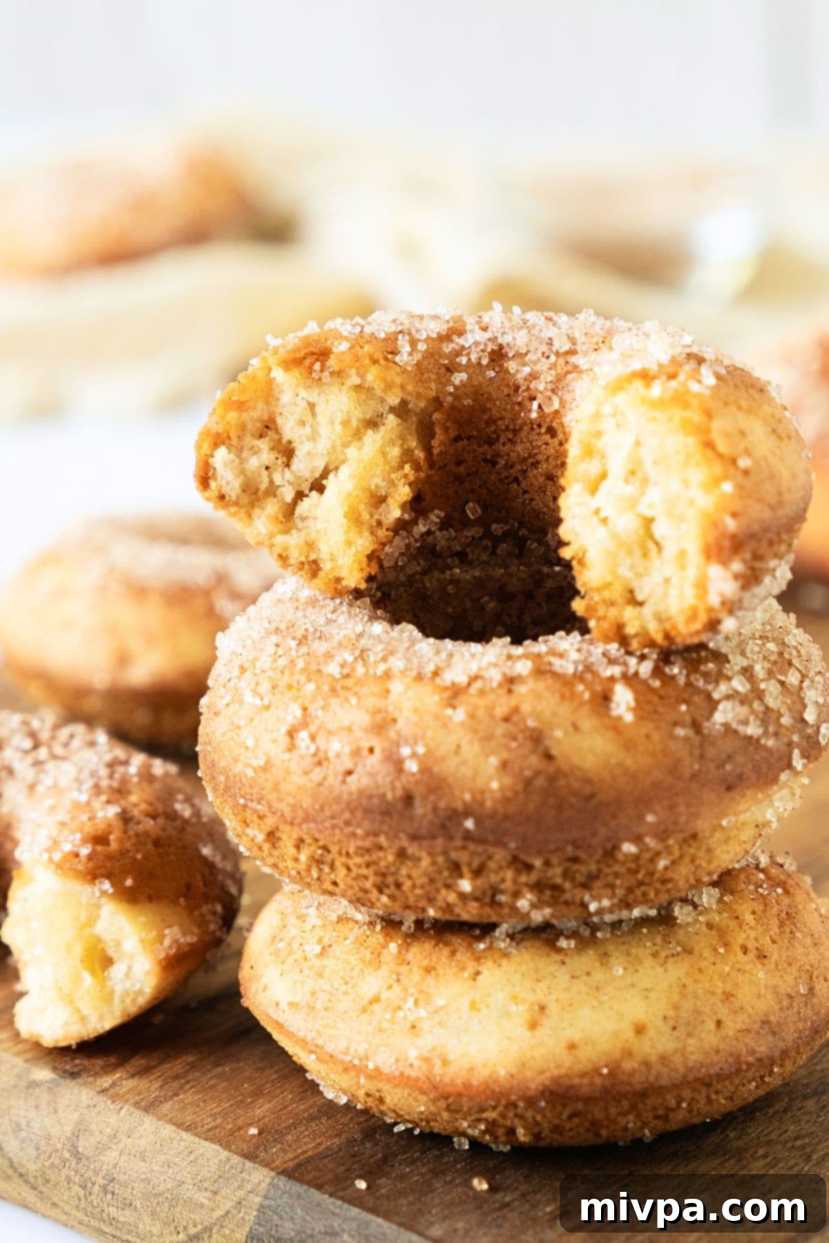 Half eaten apple cider donuts stacked up on wire rack.