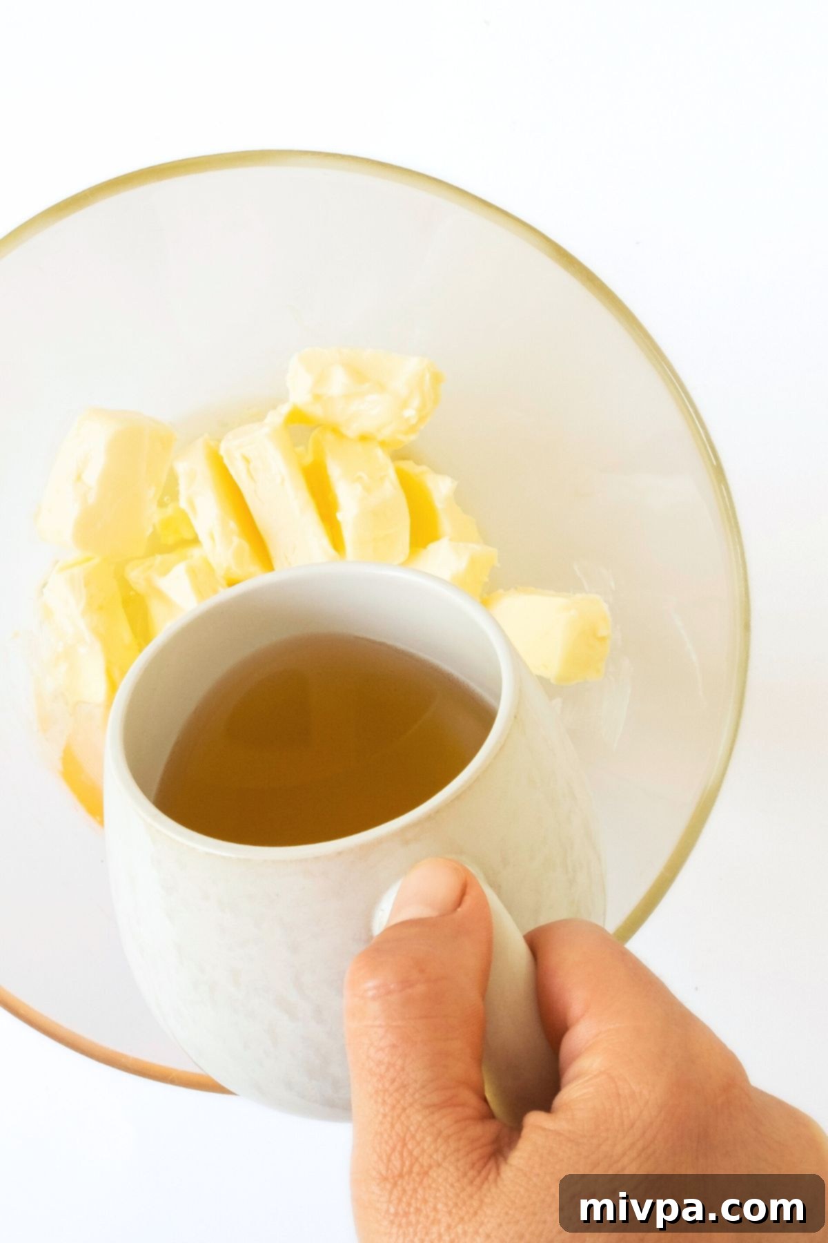 Pouring apple cider into a bowl of butter