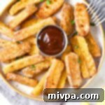 A plate of golden halloumi fries served with a small bowl of dipping sauce.