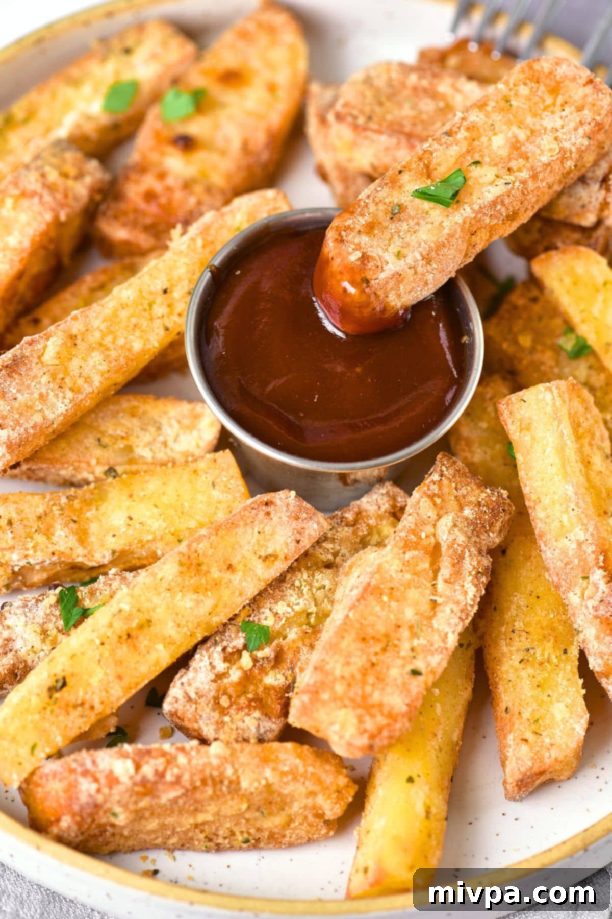 A close-up shot of a hand dipping a golden halloumi fry into a small bowl of ketchup, highlighting its crispy exterior.