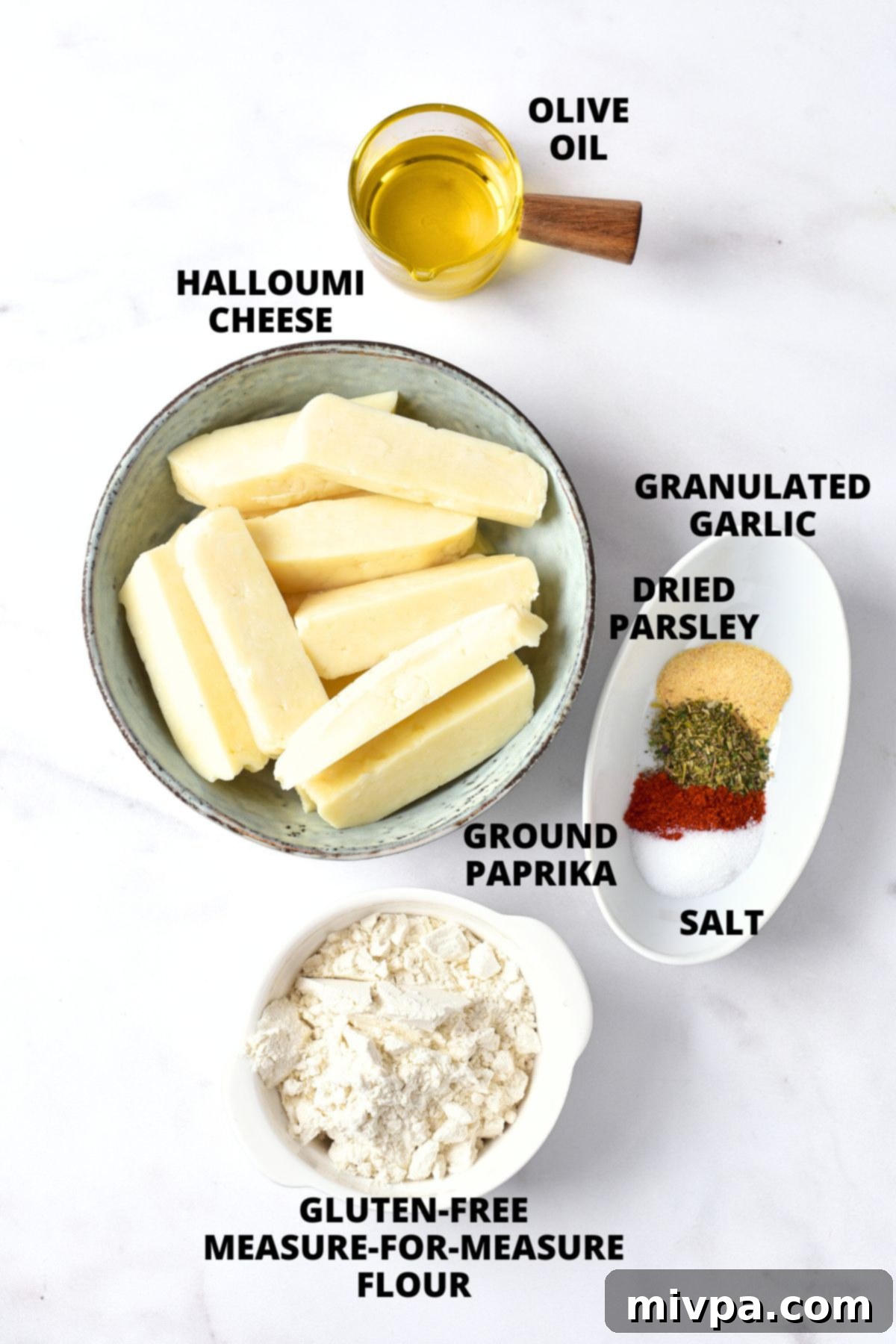 All the fresh ingredients for air fryer halloumi fries recipe, including a block of halloumi, gluten-free flour, olive oil, and various spices, neatly laid out on a marble board.