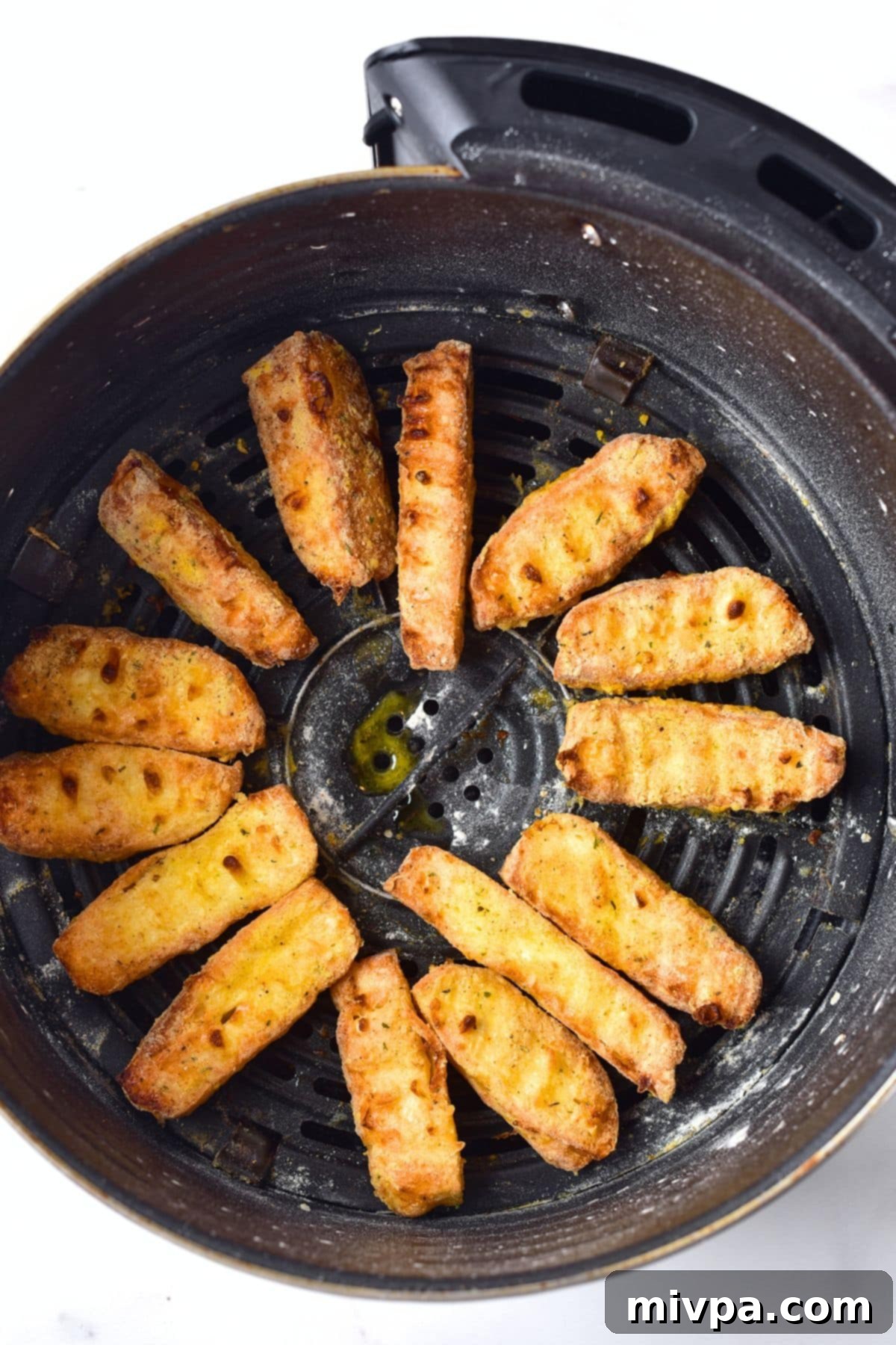 Freshly cooked, golden-brown halloumi cheese fries in the air fryer basket, looking perfectly crispy and ready to serve.