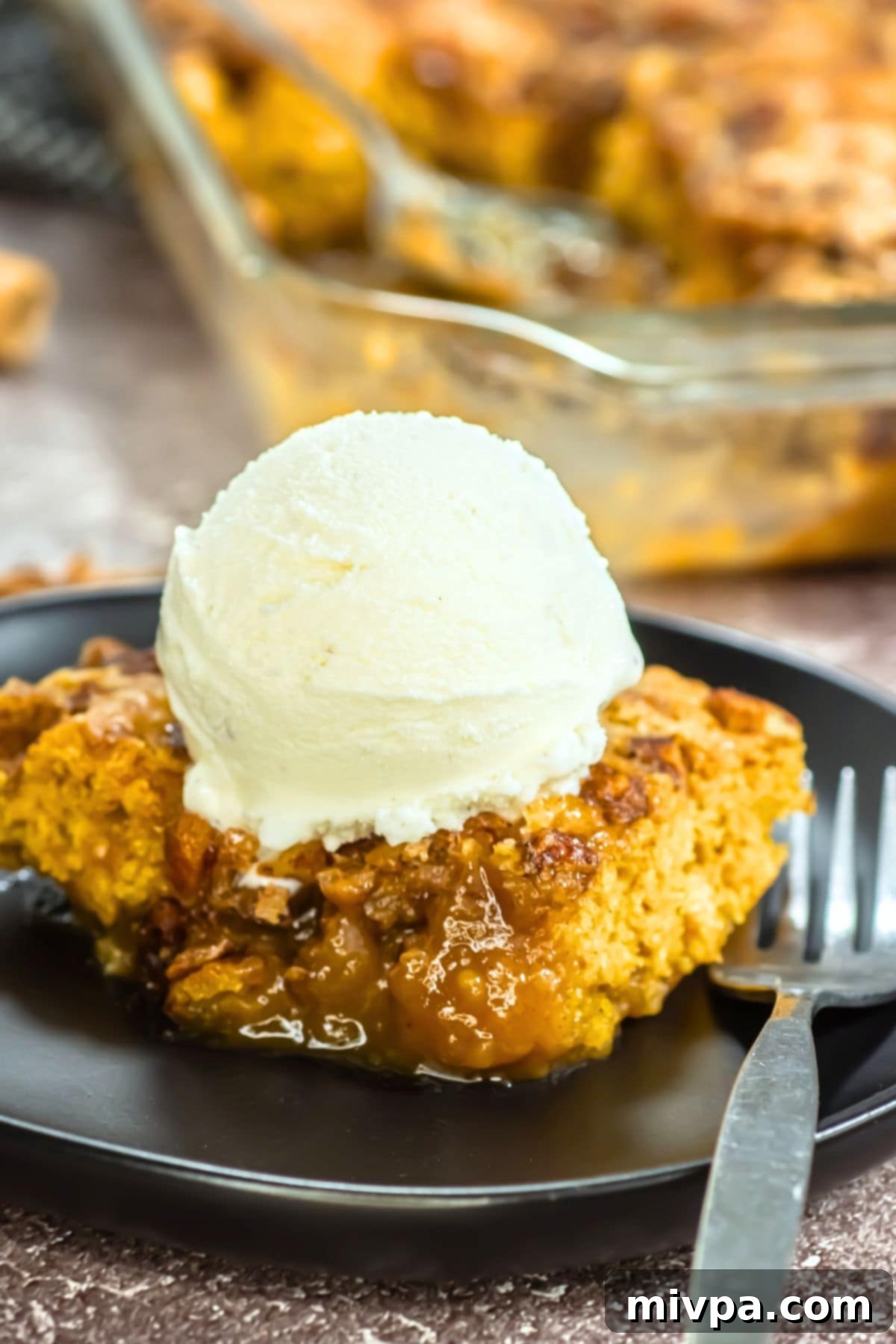 Up close view of a plate of pumpkin cobbler topped with ice cream.